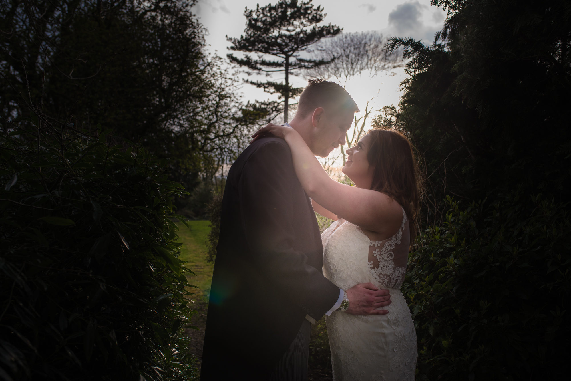 The sun shines in between the bride and grooms heads.