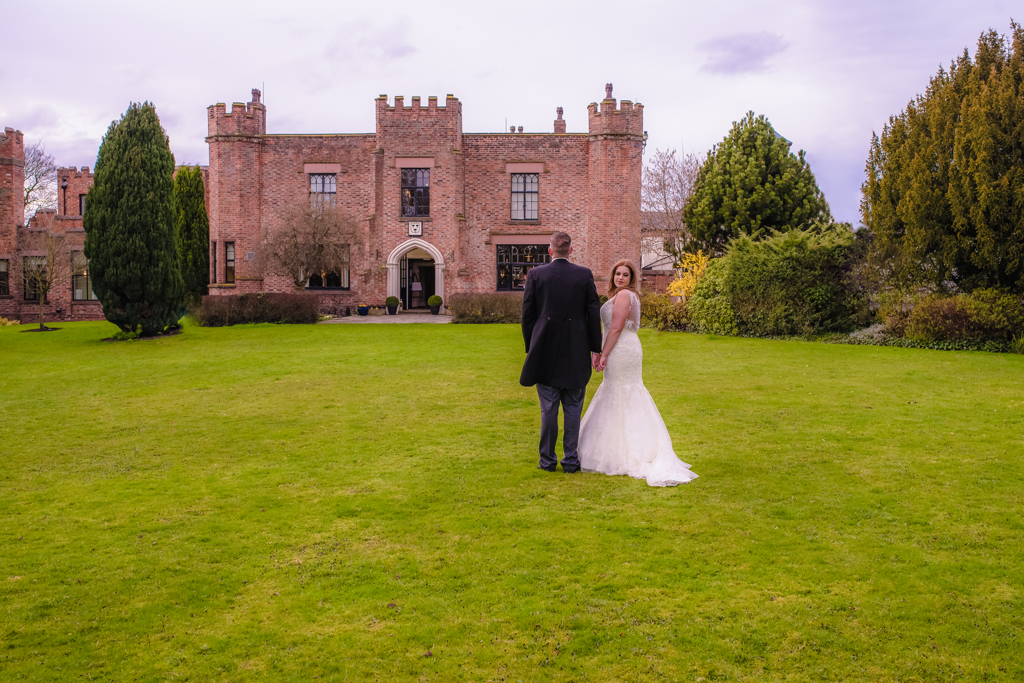 Bride glances round as they walk towards Crabwall Manor.