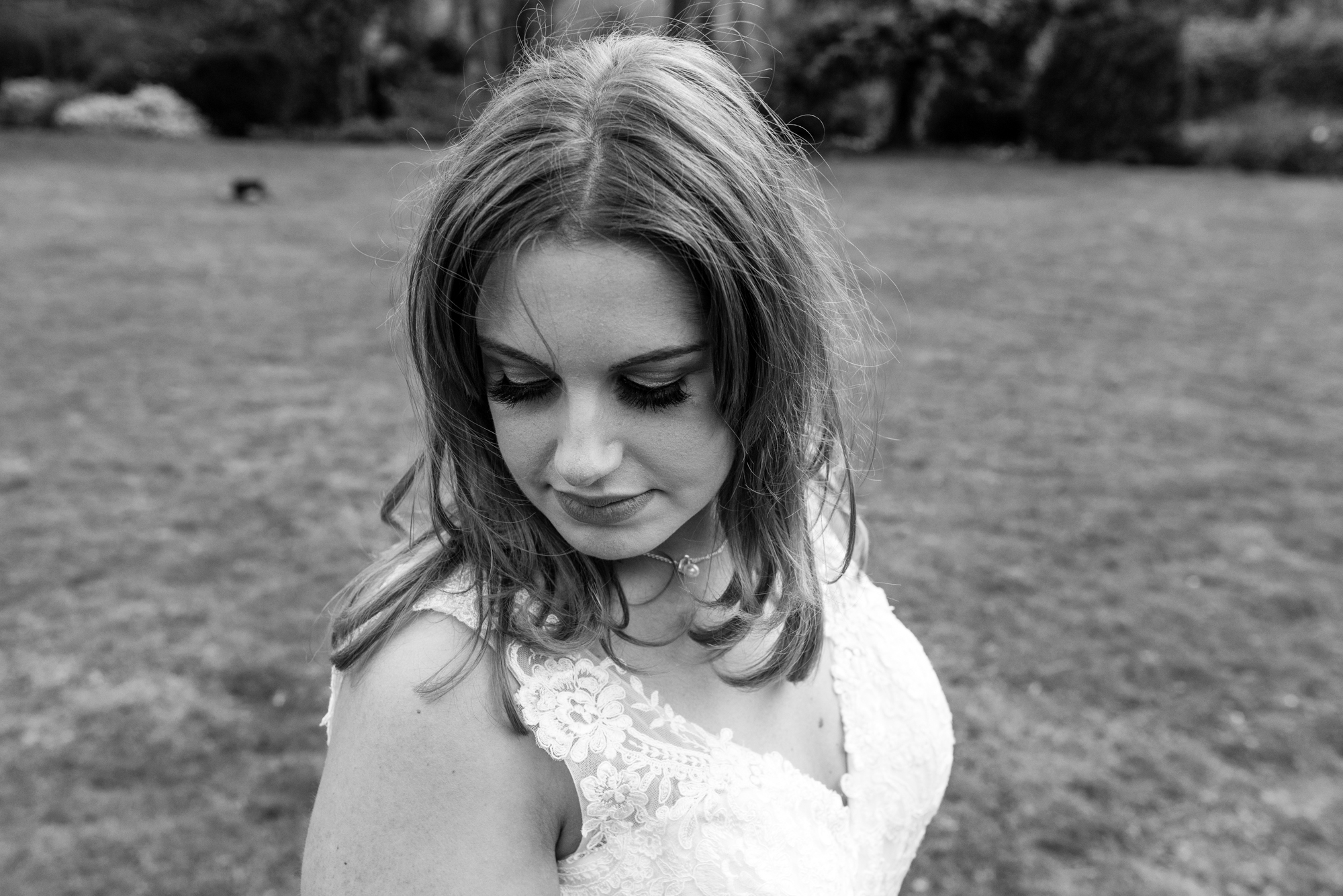 Black and white image of the bride looking down towards the ground.