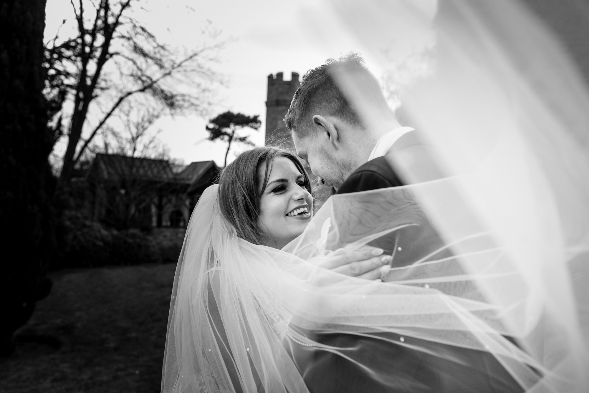 The veil covers the brides face as she has a photo in front of crabwall manor.