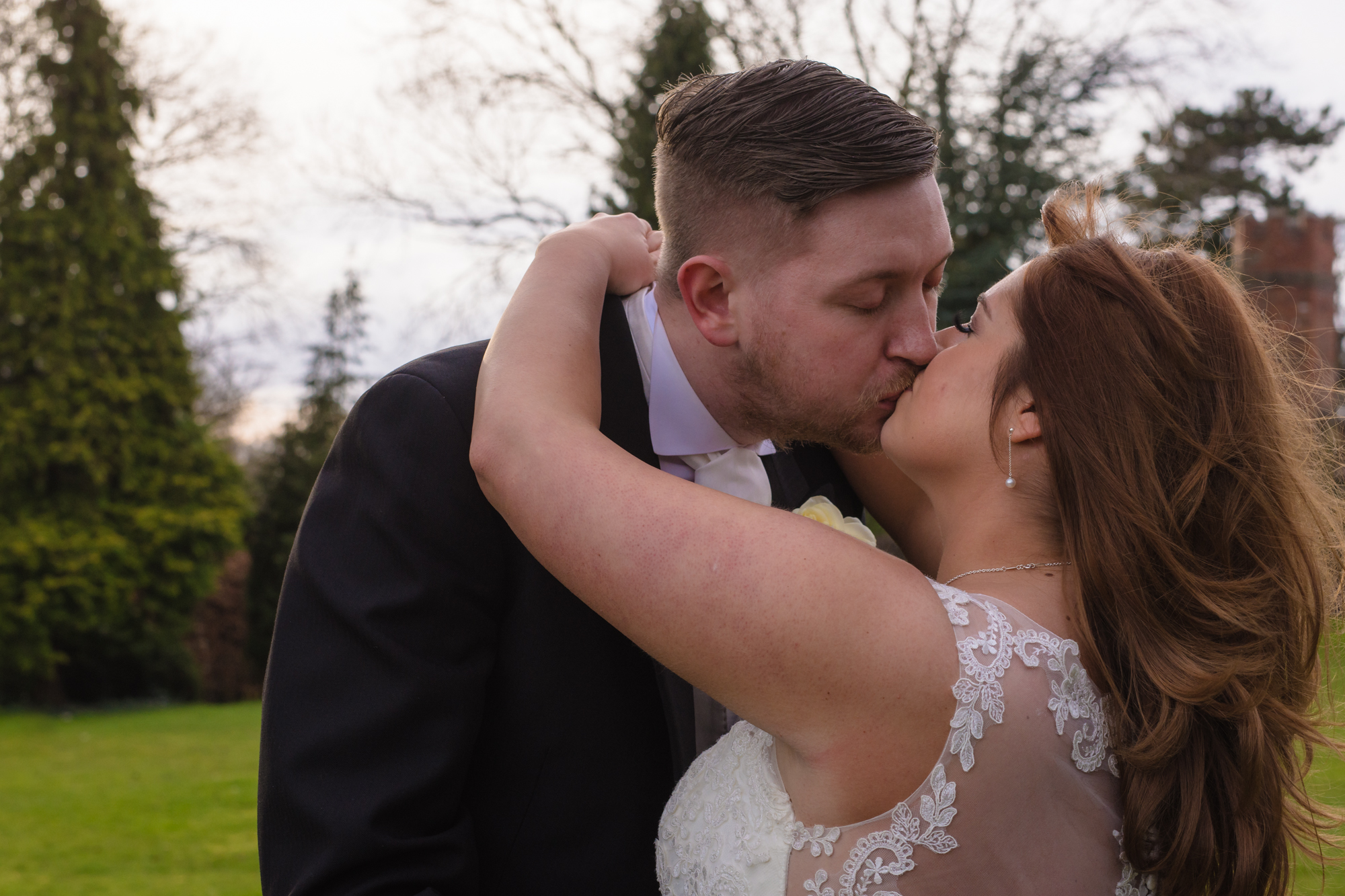 The bride and groom share a kiss together outside crabwall manor.