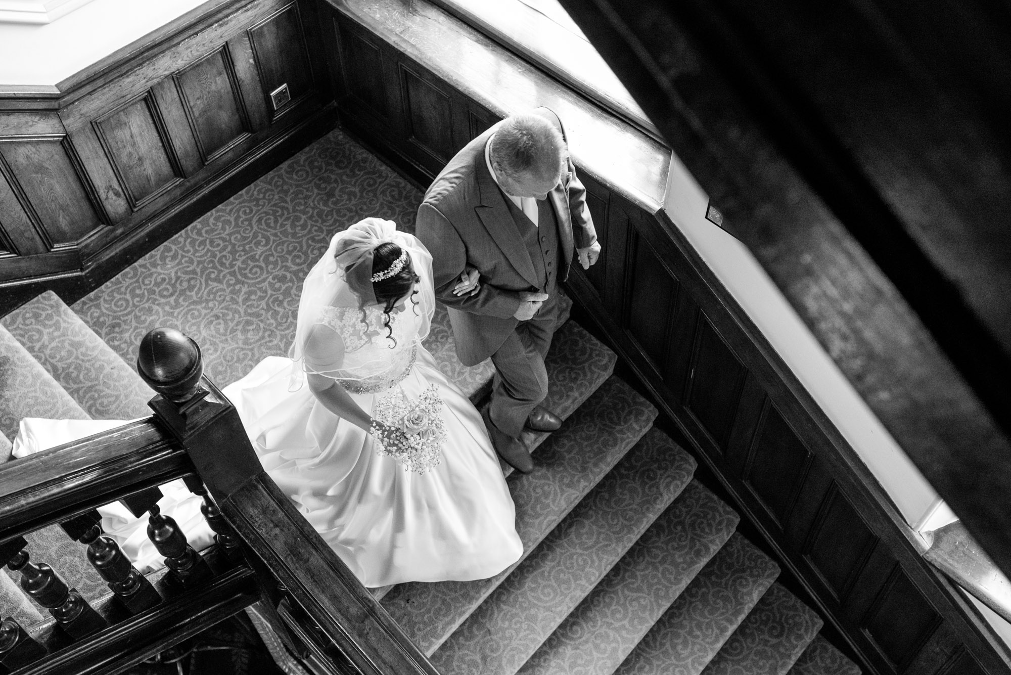 Father of the bride leads his daughter down the stairs
