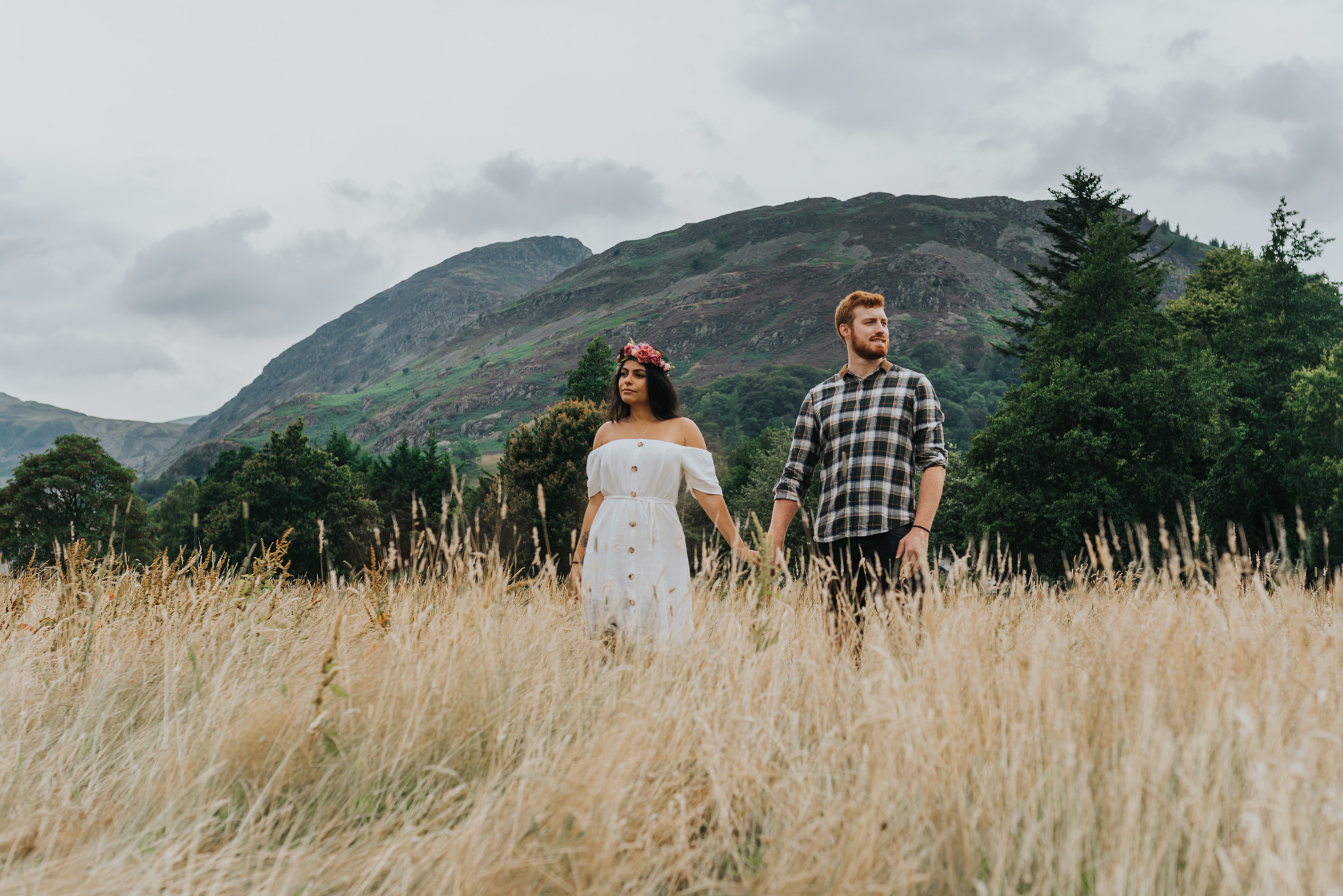 Holding hands in the grass looking away