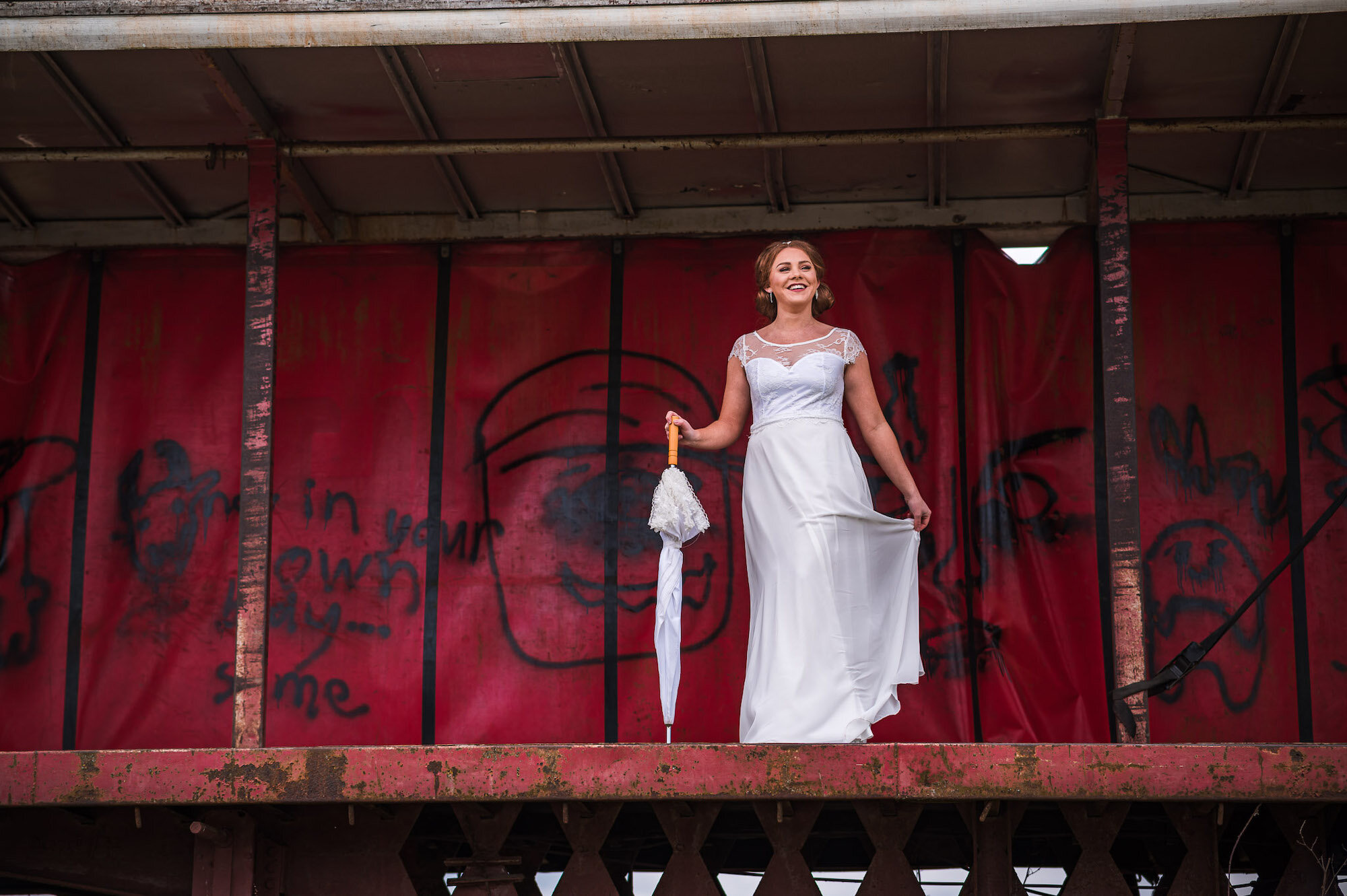 Bride standing on a trailer with an umbrella
