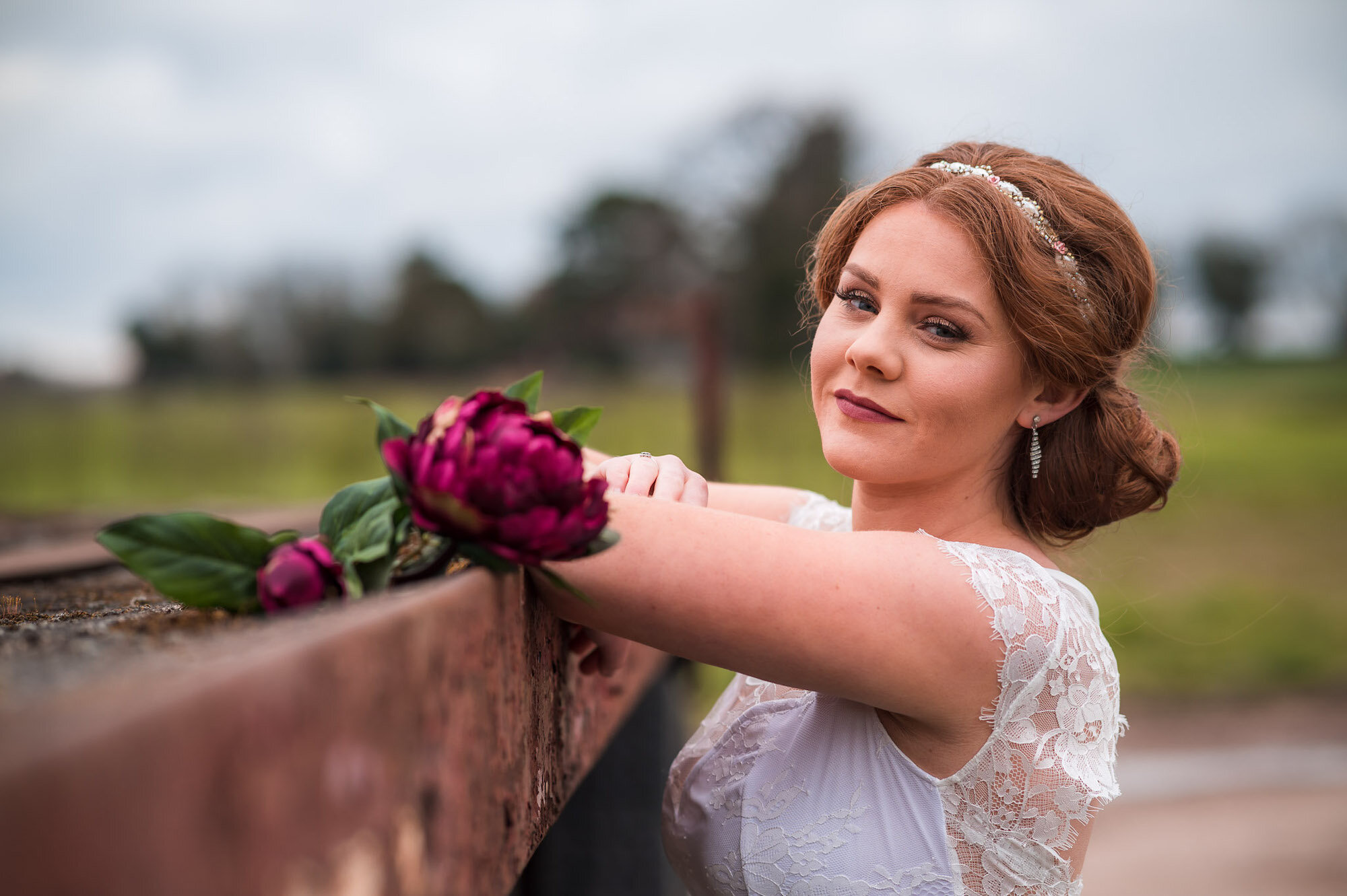 Bride leaning up against a trailer