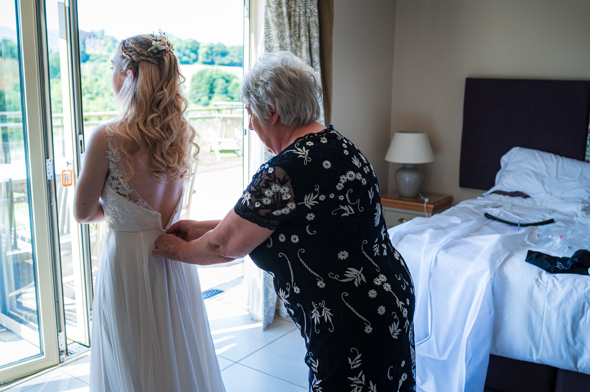Mum doing up the bride's dress