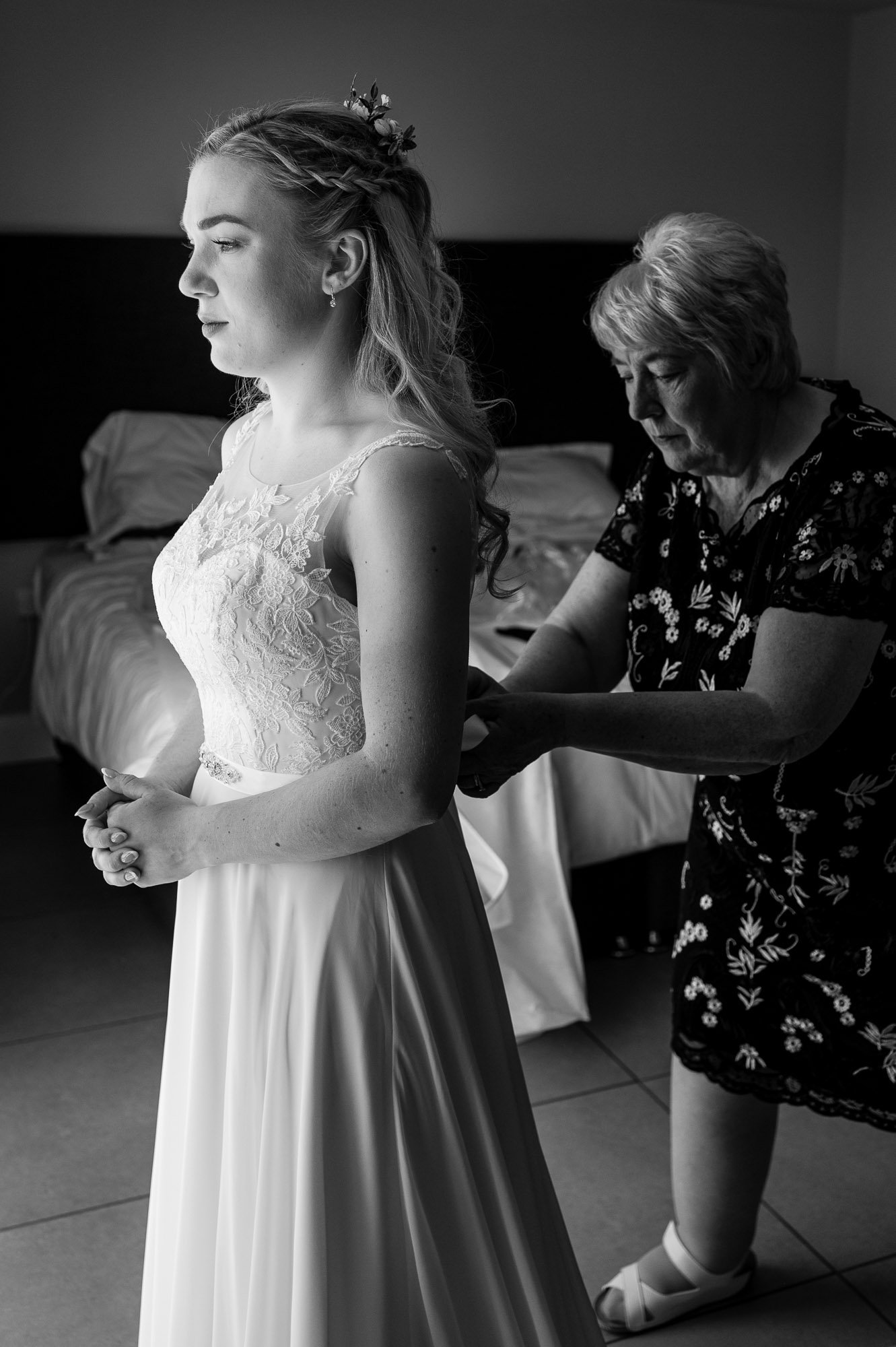 Black and white - bride's dress being done up by mum