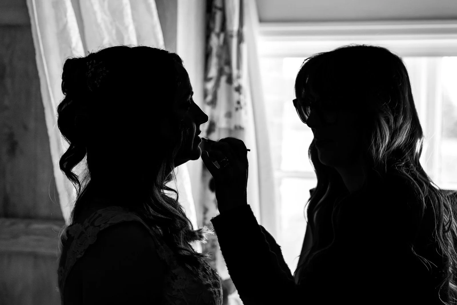 Silhouette of bride getting make up done