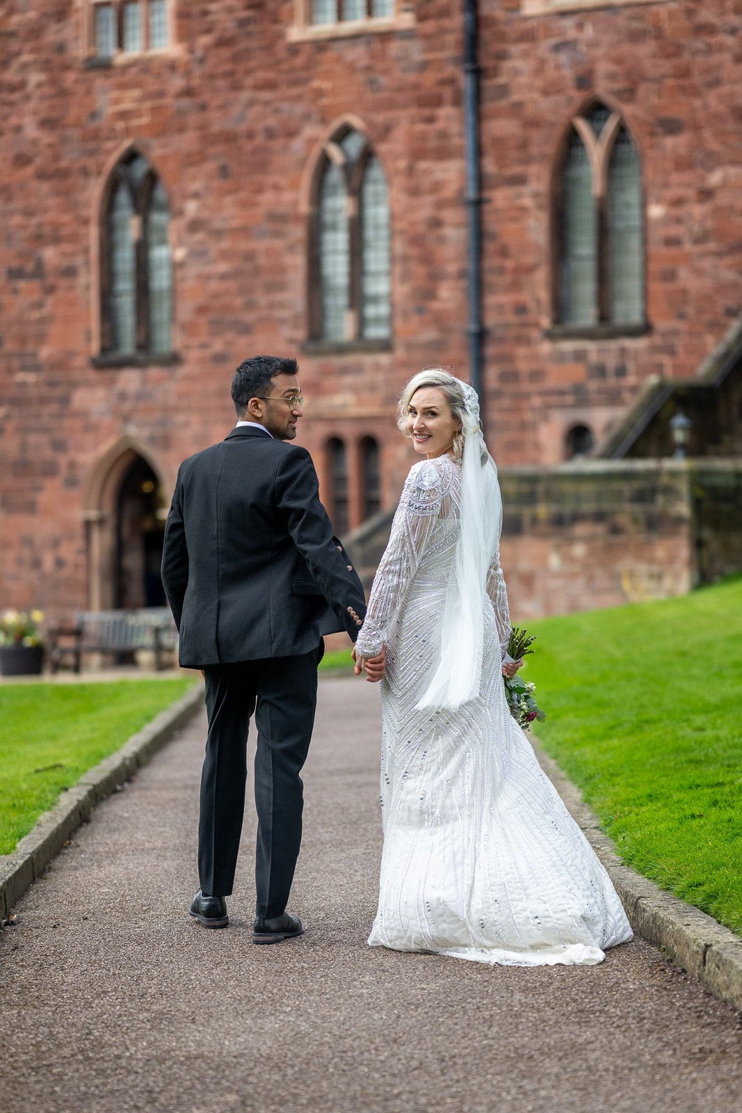 Bride and groom walking, bride looking back at the camera