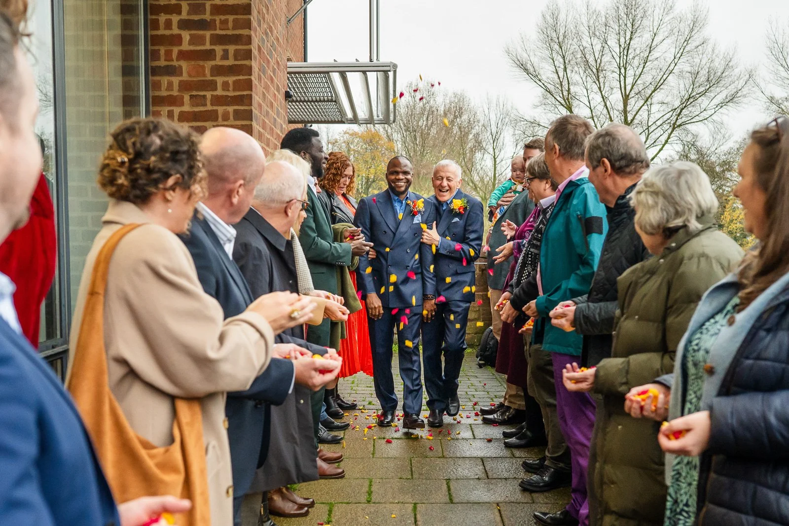 Same sex couple walk down confetti line