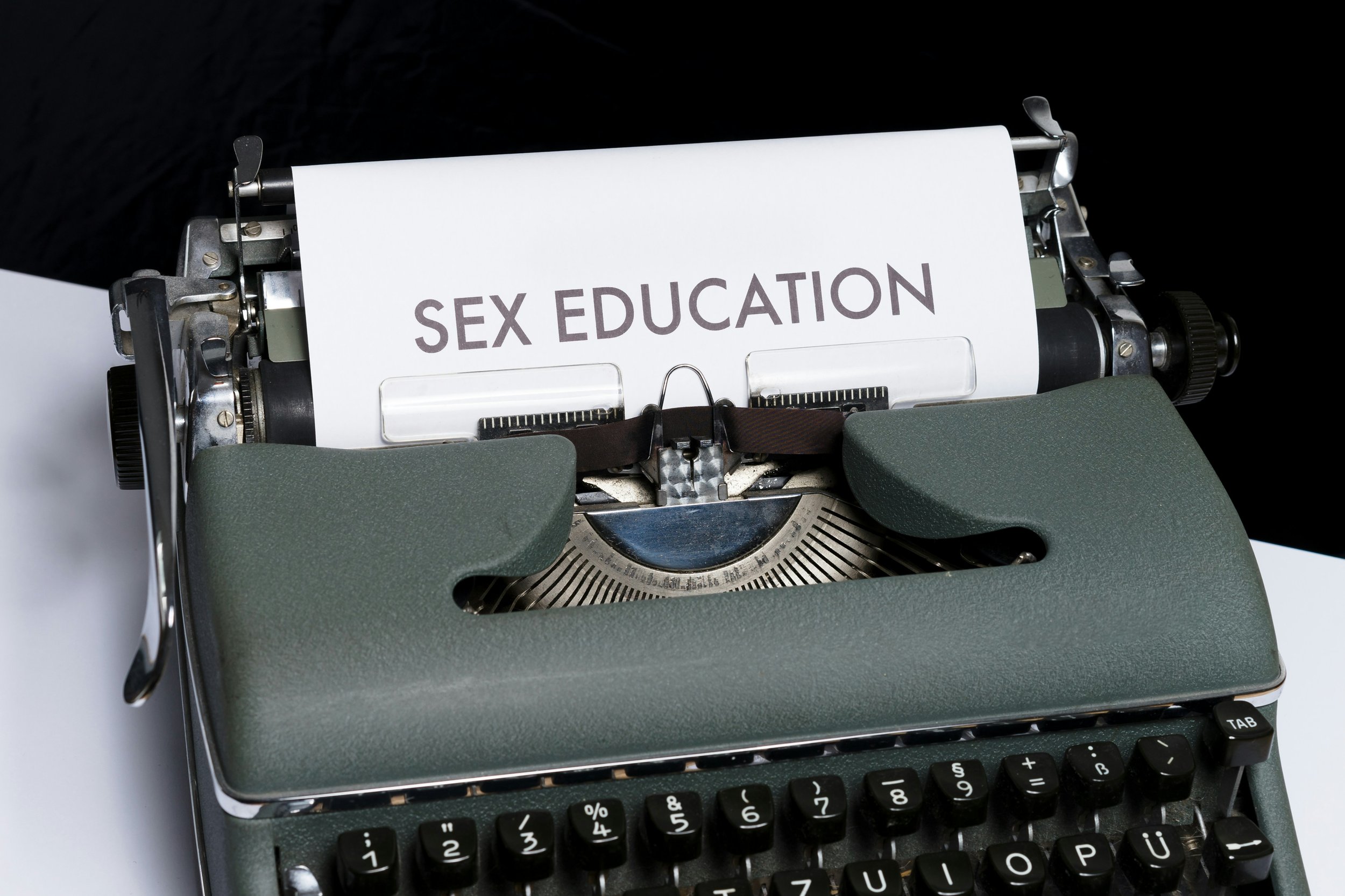 The words "sex education" are typed in all caps on a piece of paper in a typewriter.