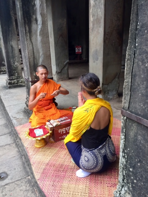 Ashlee receiving sai sin from a Buddhist monk inside of Angkor Wat.