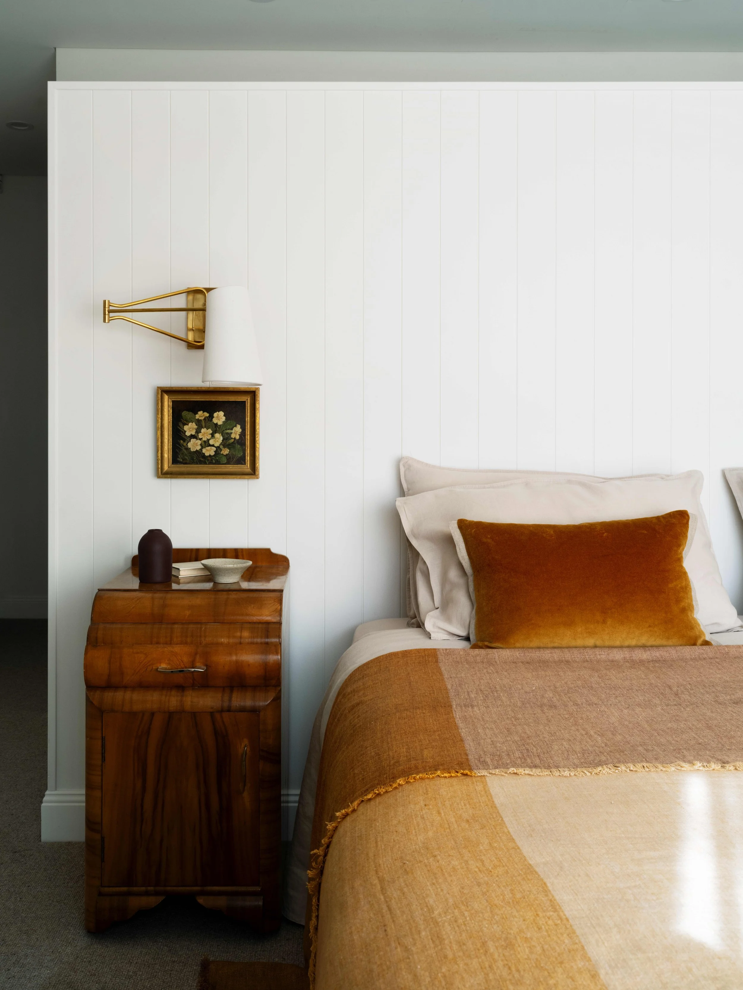 Warm toned bedroom with art and wall sconce