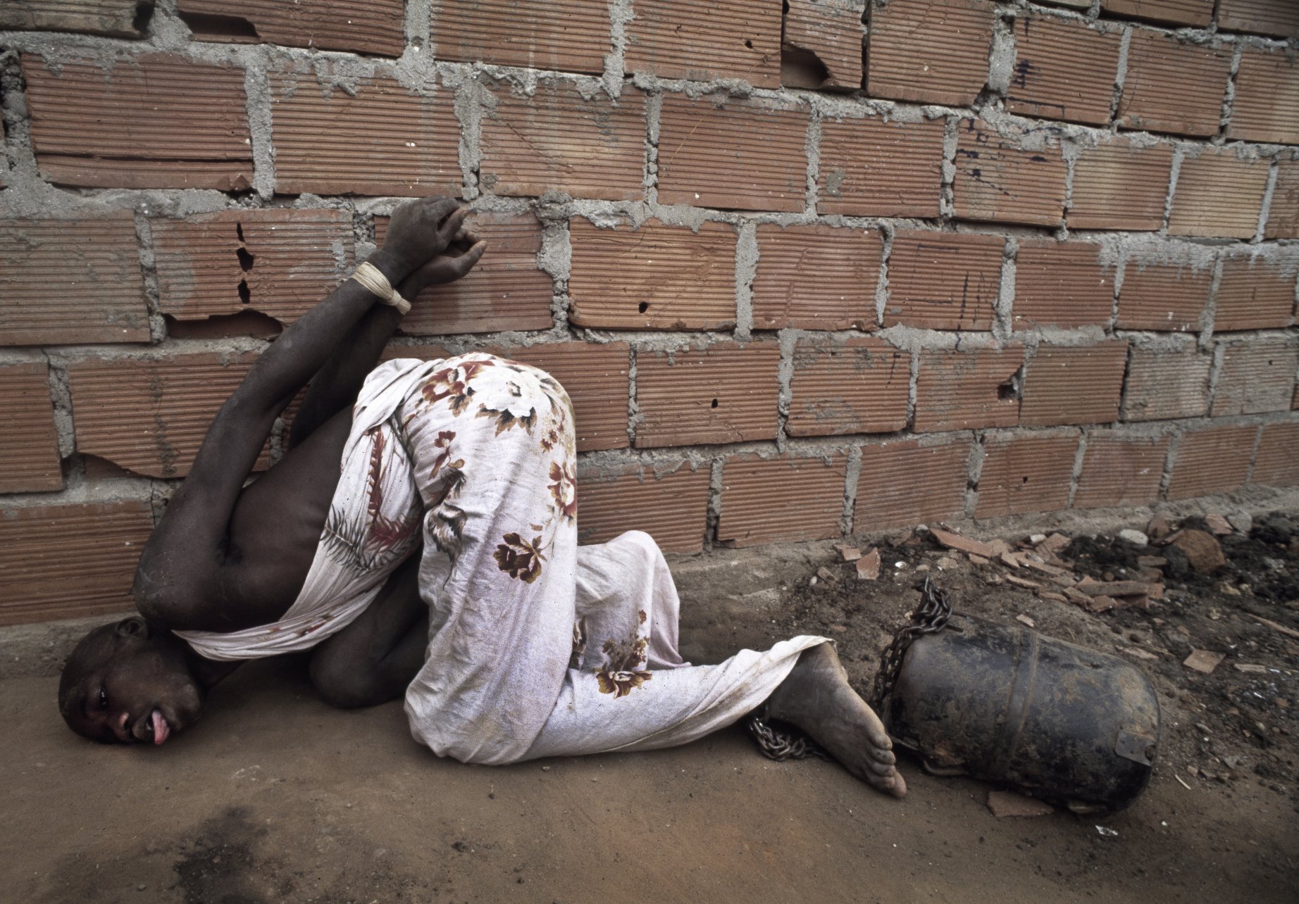  A former combatant of Angola's long running civil war is chained to an engine  part at Papa Kitoko's mental asylum, Luanda, Angola, 1993 