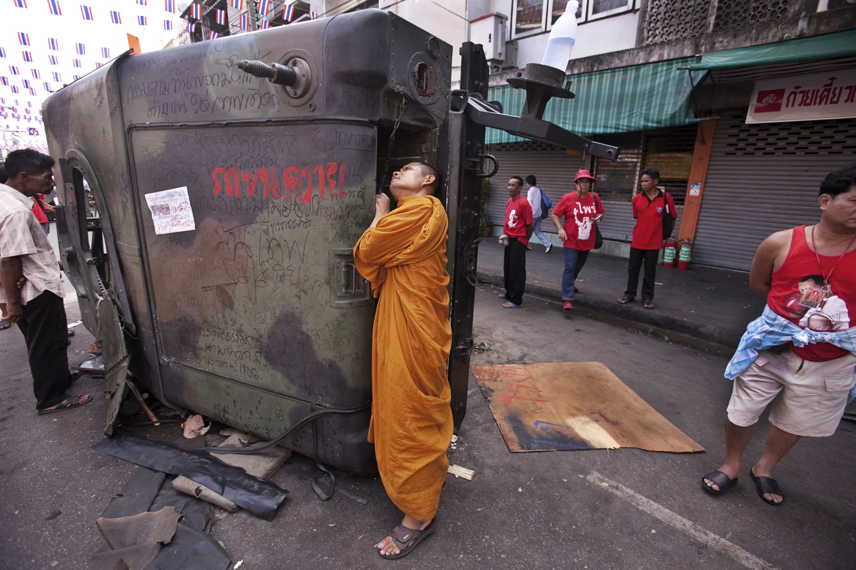 In 2010 in Bangkok at least 90 people died and more than 2,000 were wounded in clashes between the “Red Shirts” and the Thai military. In This Photograph: A Monk surveys a destroyed Thai Army APC near Khaosan Rd, Bangkok.