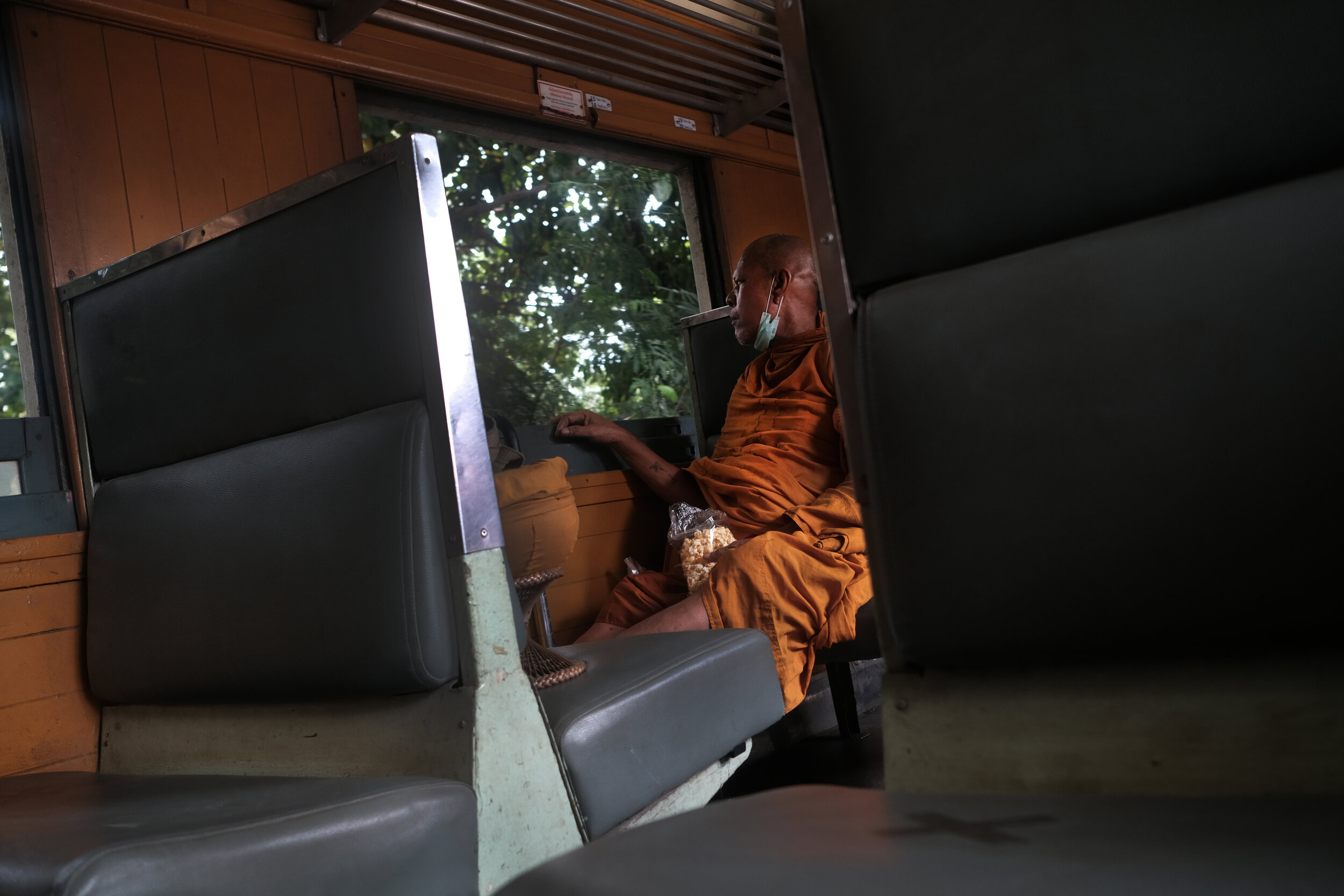  Popcorn and reflection. A Buddhist Monk making the return journey to Bangkok Thonburi Station. 