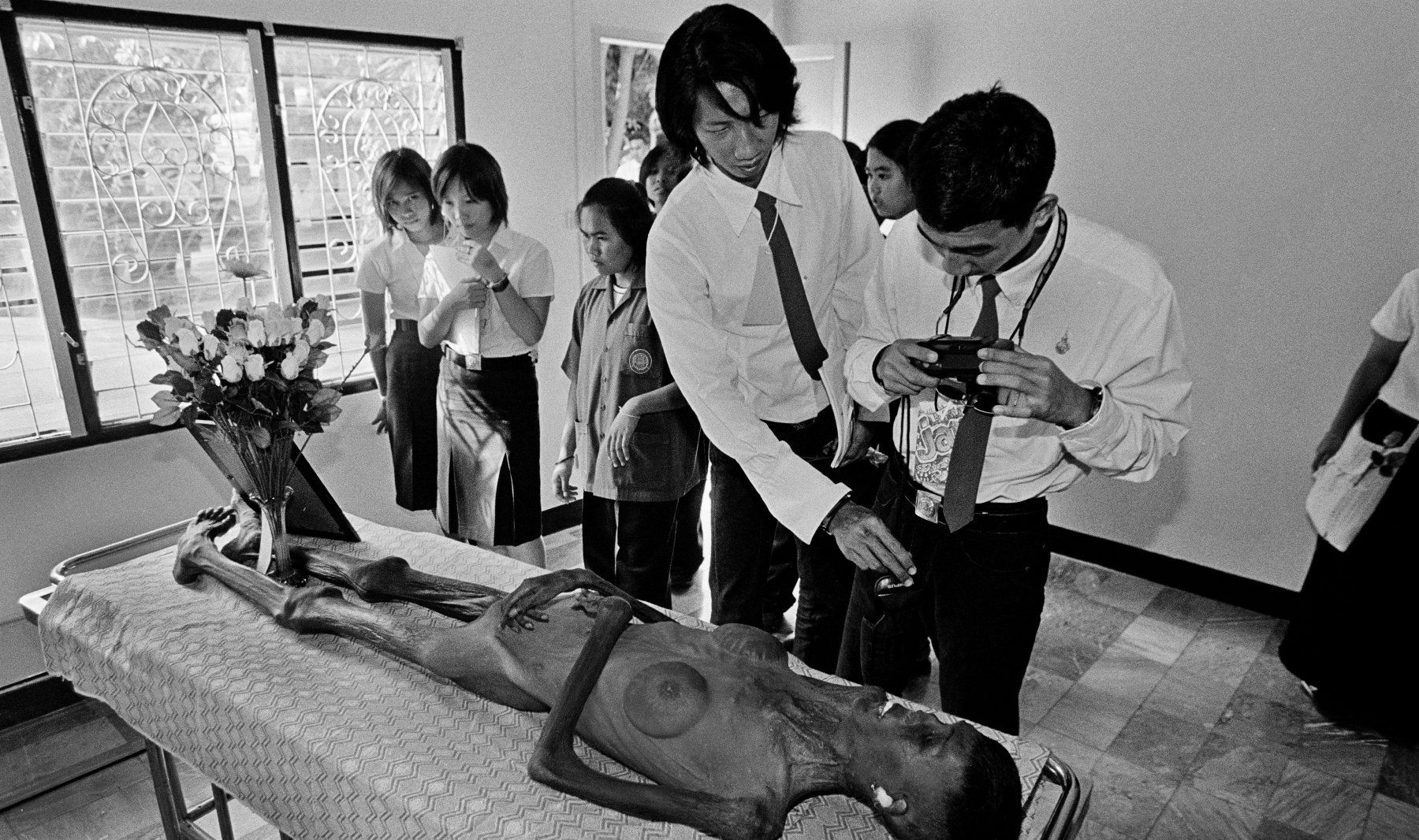  Students view a deceased woman exhibited at the Wat Prabat Nampu AIDS Museum in Lopburi, north of Bangkok. Thailand. 2003.  