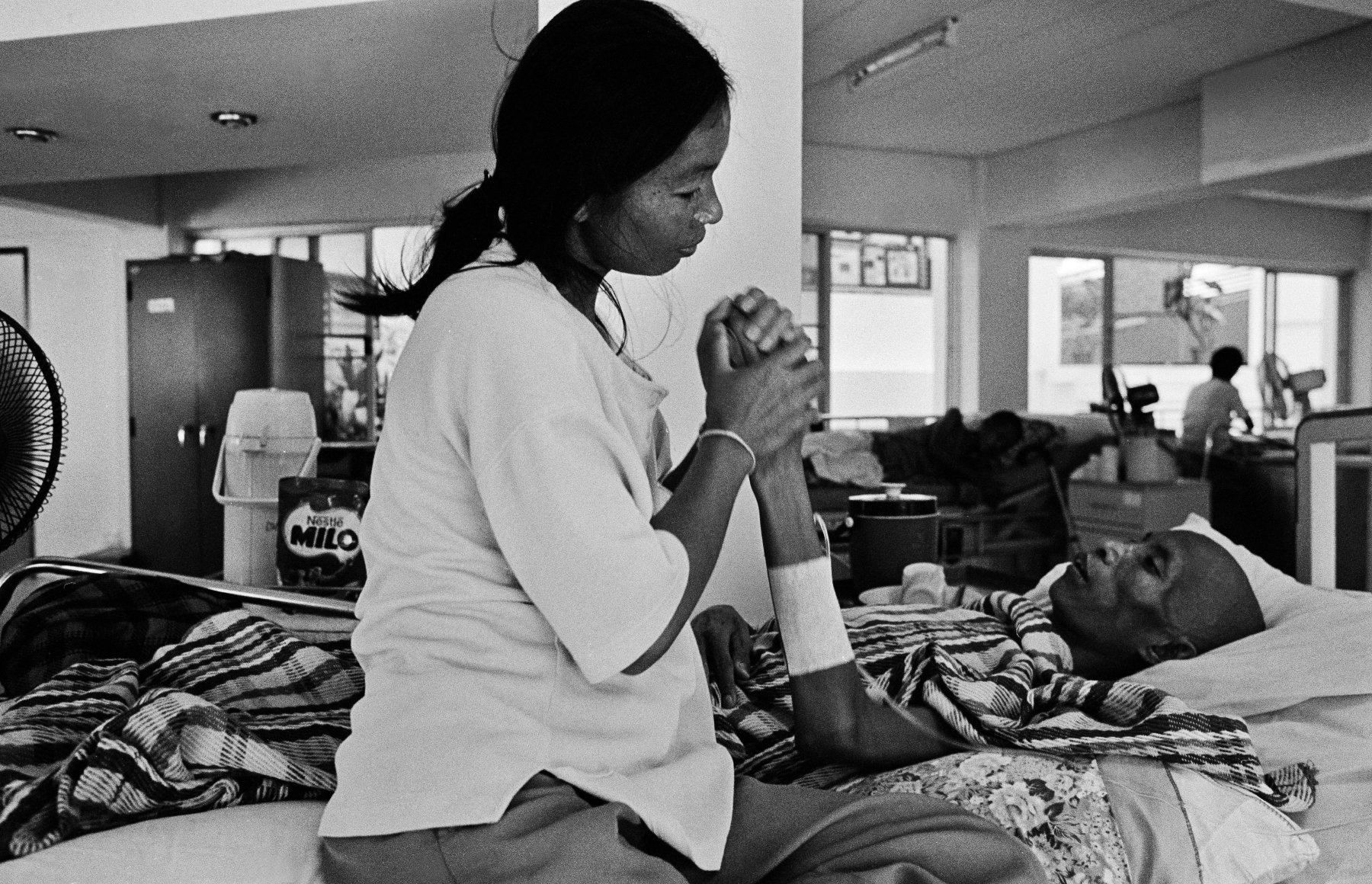  “Care” A wife cares for her husband at Wat Prabat Nampu. Wat Prabat Nampu is a Buddhist temple and a hospice for those living with HIV. Lopburi, Thailand. 2003. 