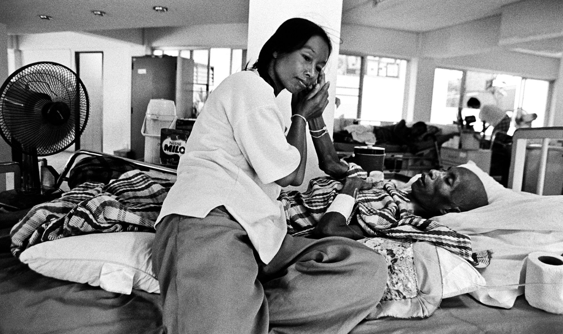  “Care” A wife cares for her husband at Wat Prabat Nampu. Wat Prabat Nampu is a Buddhist temple and a hospice for those living with HIV. Lopburi, Thailand. 2003. 