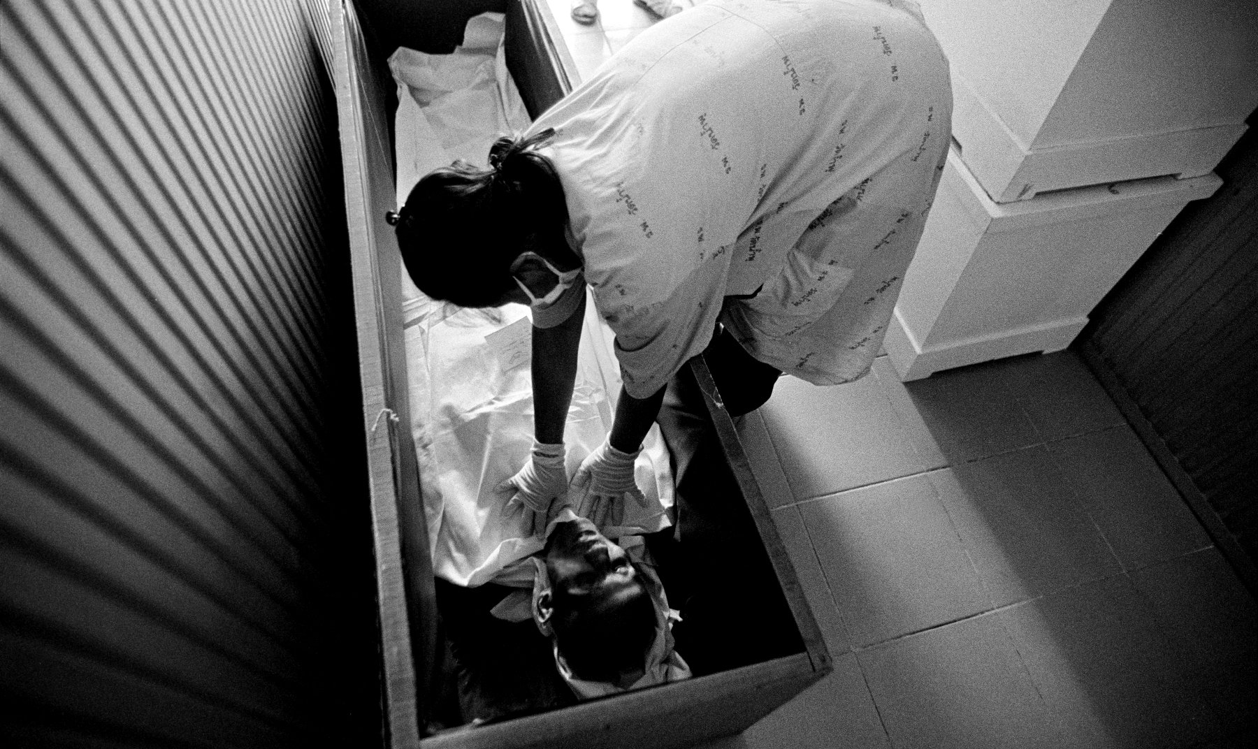  “Preparation” A volunteer carer prepares a deceased patient for cremation at Wat Prabat Nampu. Wat Prabat Nampu is a Buddhist temple and a hospice for those living with HIV. Lopburi, Thailand. 2003. 