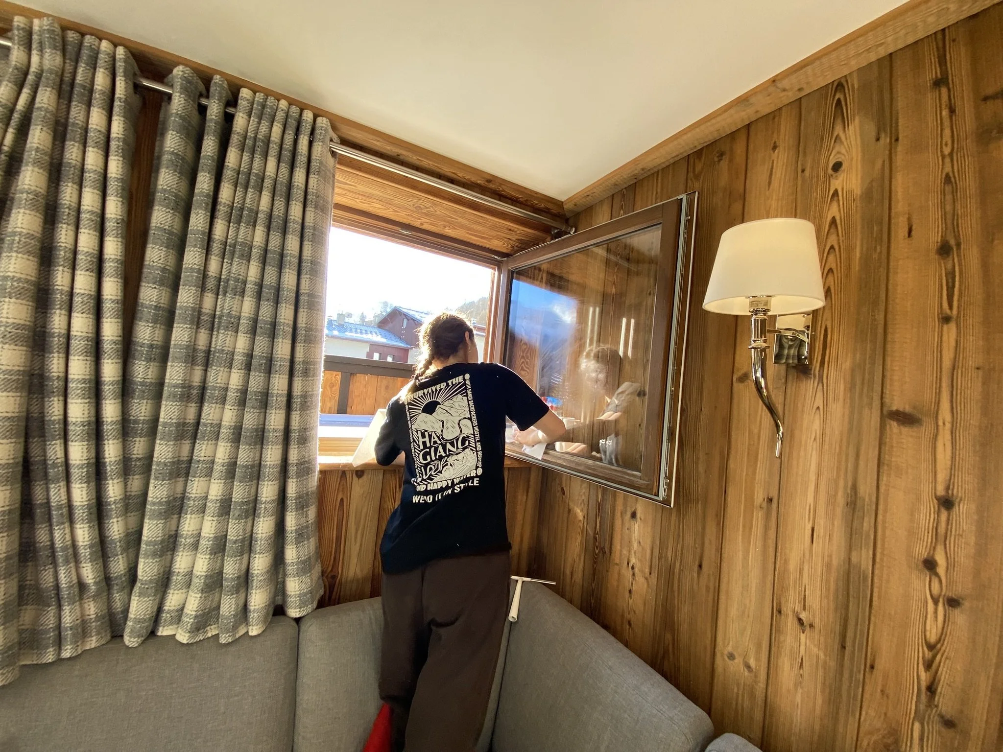 Chalet girl cleaning the windows on a sunny day in her chalet