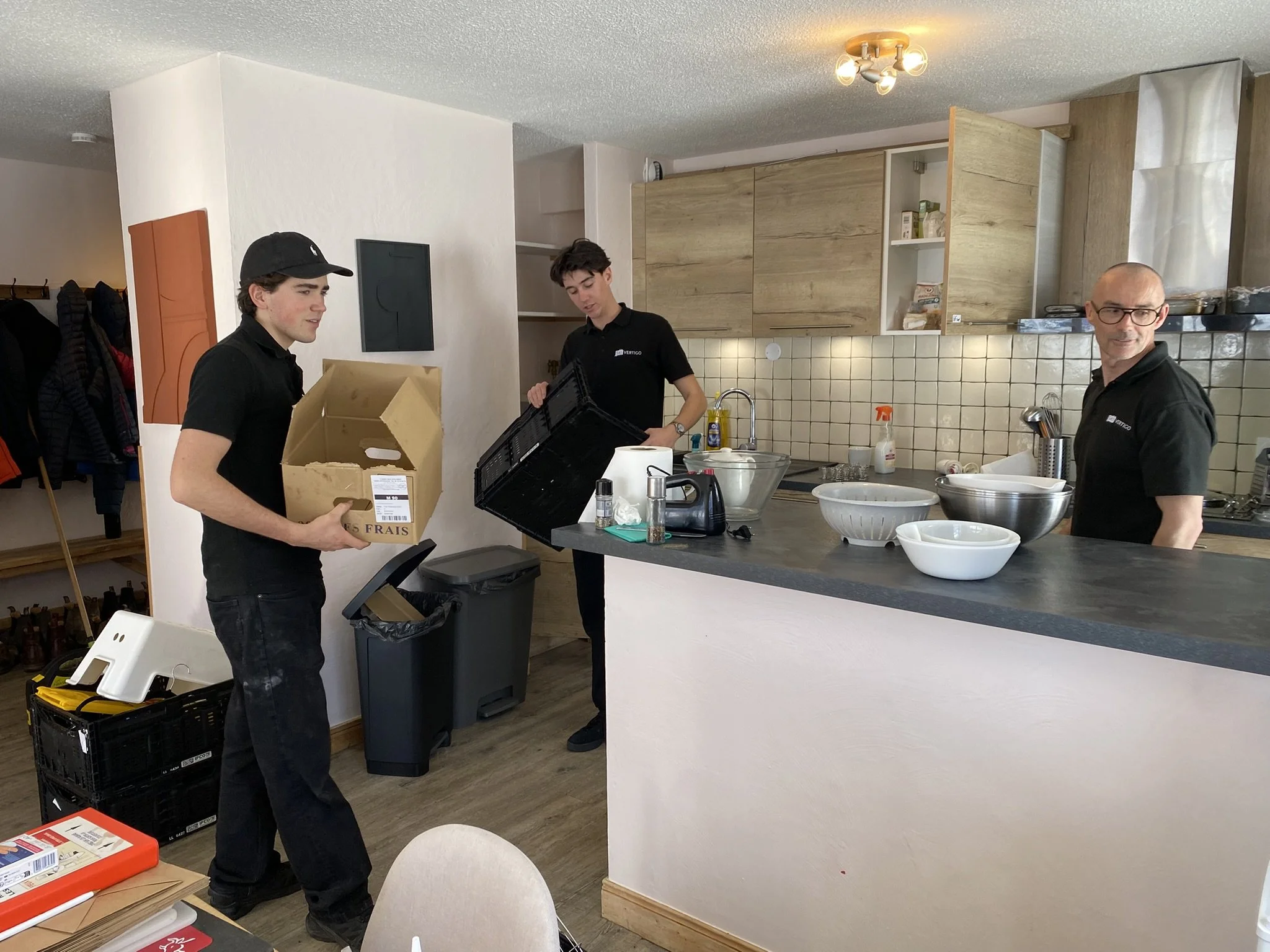 Three hosts working as a team to sort out deliveries in the kitchen and put items away
