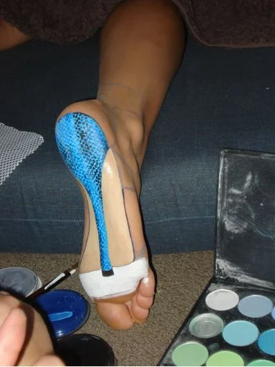 I had the model stand on a table and I marked out the outline of the shoe detail which you can see in purple pencil... then she relaxed on a matress for 3 hours whilst I painted with water based paints and eye shadow for shading. You can see the material on the left hand side I used as a stencil to start the texture then went over the shapes with a fine brush and paint for highlights and lowlights.