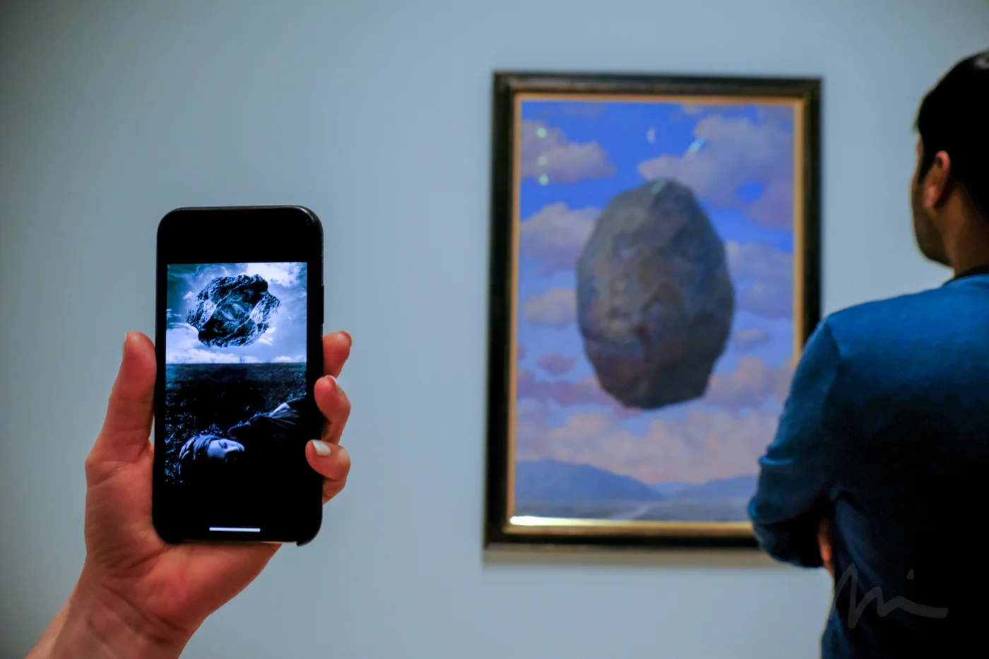 Uelsmann’s “Magritte’s Touchstone” (1965) on a phone next to one of Magritte’s floating stones at SFMOMA.