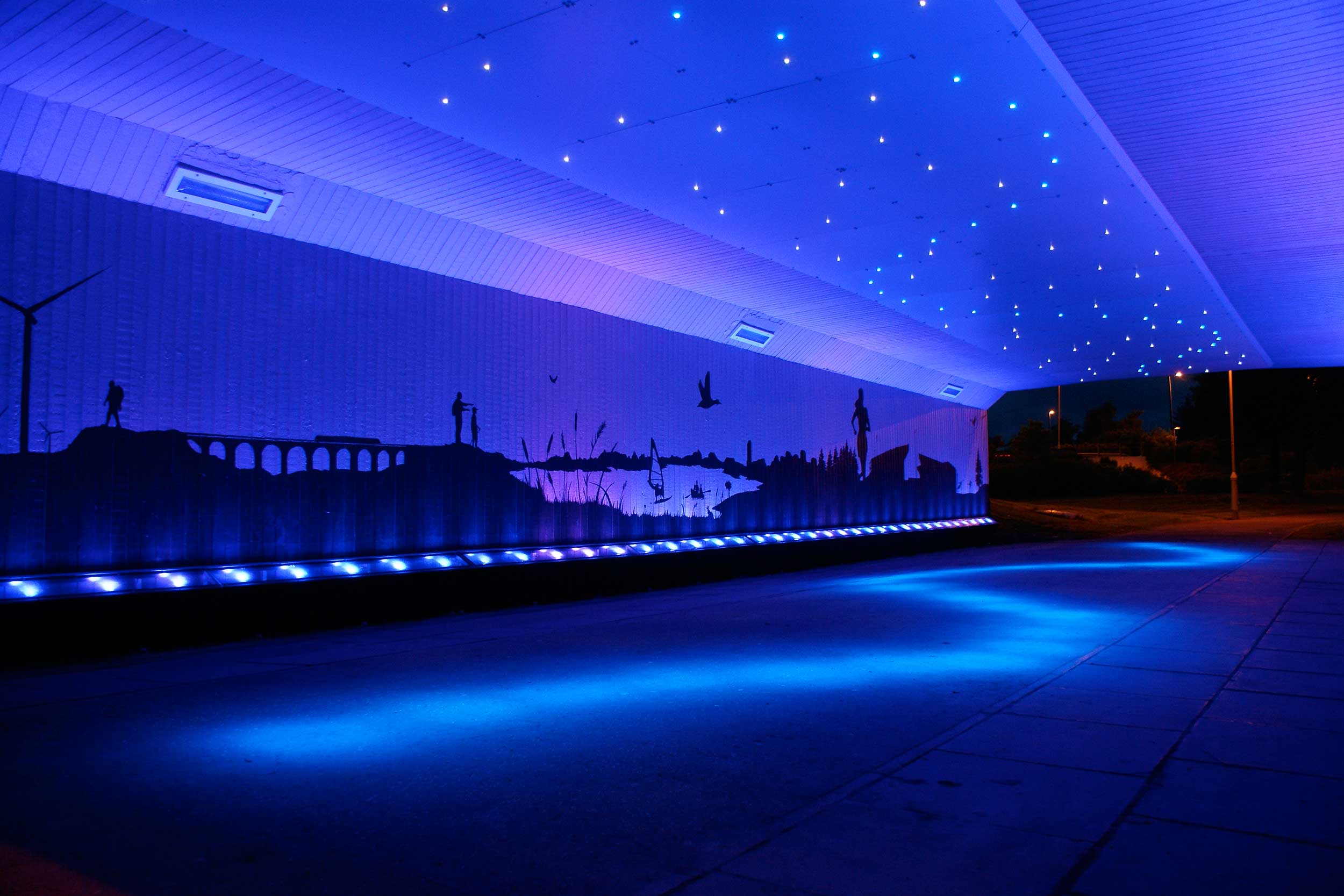 Murals on the underpass walls celebrate recognisable scenes from the local area whilst a river of light references Cumbernauld's waters.
