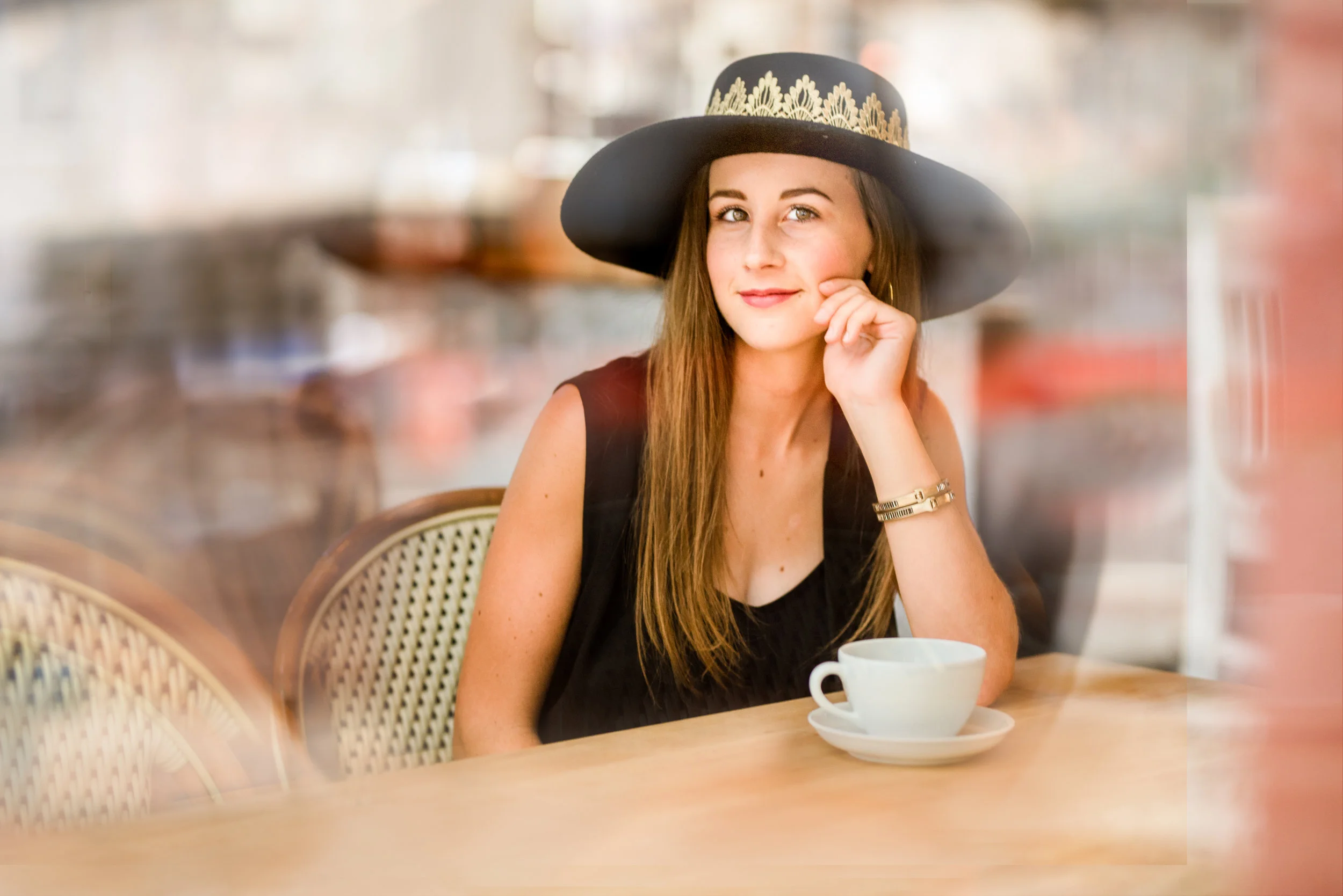Houston, TX High School Senior girl sits in coffee shoot and smiles through window.