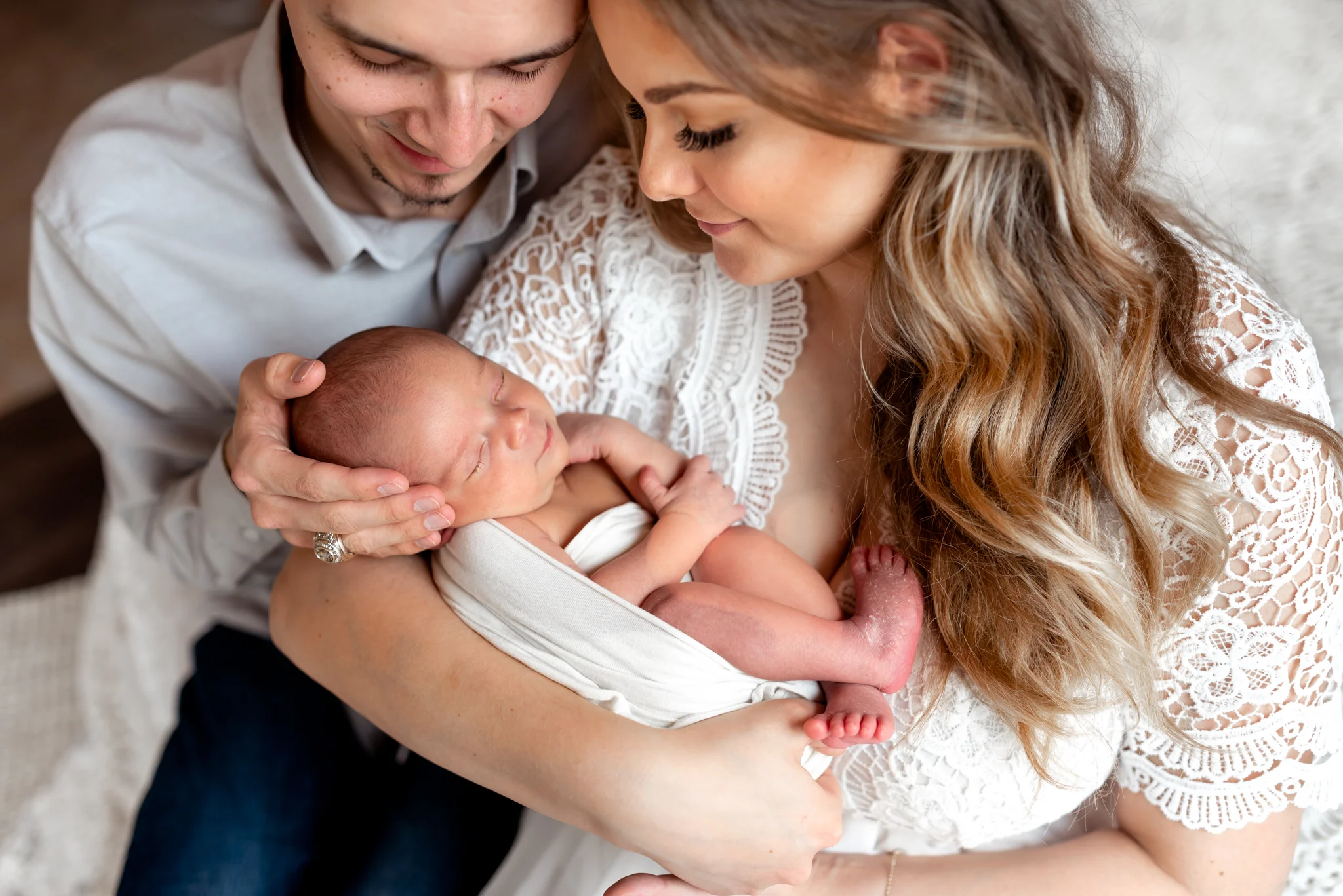 Beautiful mom and her baby girl in a natural light, boho studio with a brick wall, textures accents, peacock chair, and neutral details.