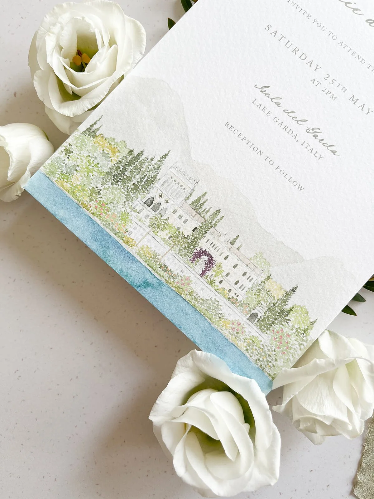 Close up of wedding invitation with watercolour venue illustration of Isola del Garda in Italy