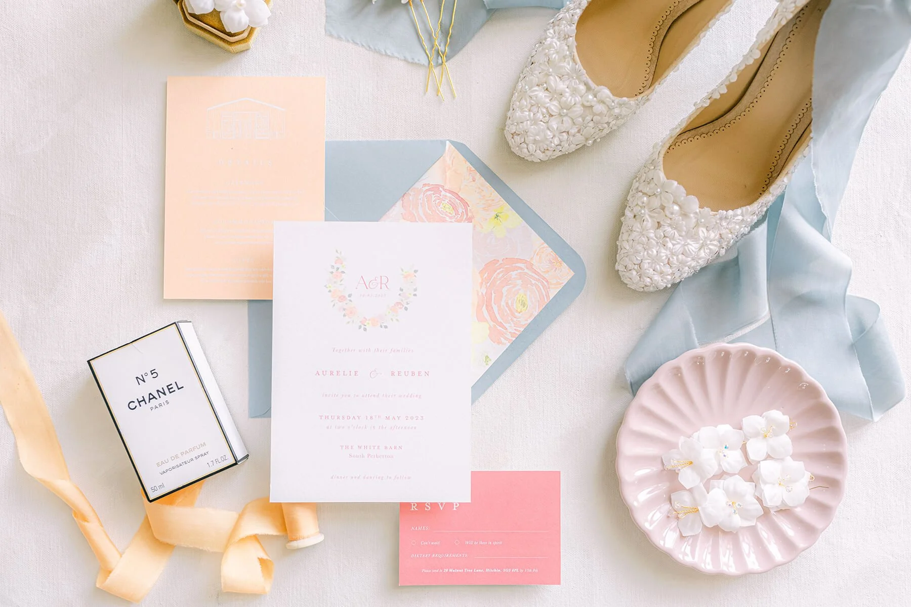 wedding invitation suite flat lay with invite, details card and rsvp card, paired with dusty blue envelope and watercolour floral envelope liner