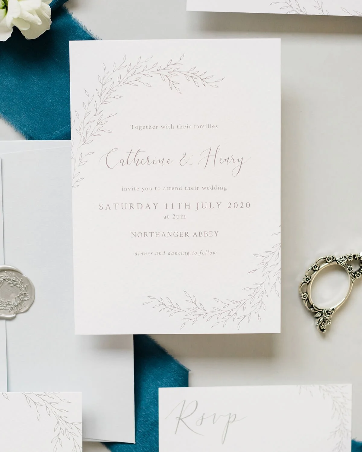 close up of A6 wedding invitation with hand drawn botanical wreath in grey