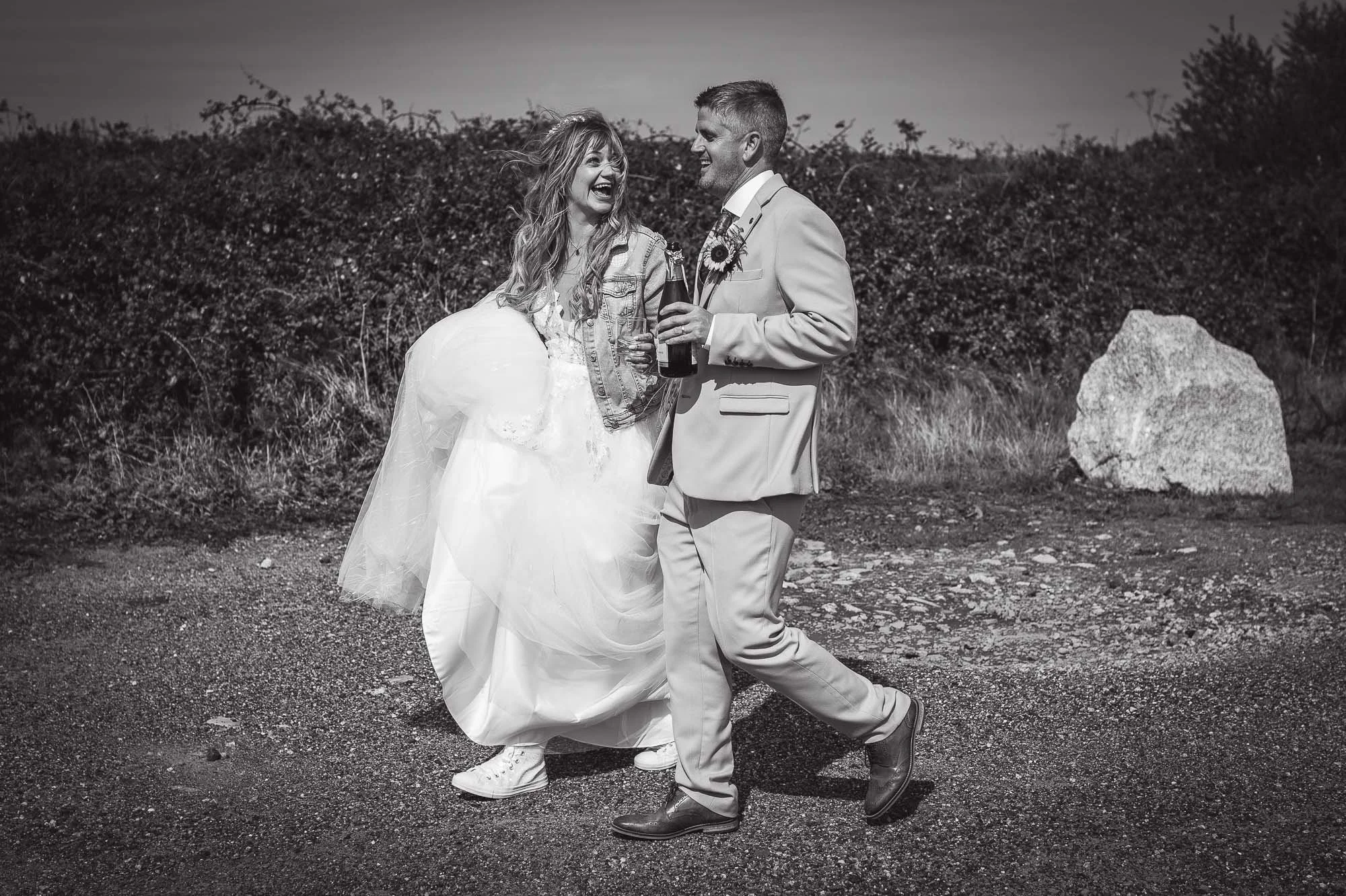 newlyweds_walk_with_champagne_laughing_Perranporth_cornwall.jpg
