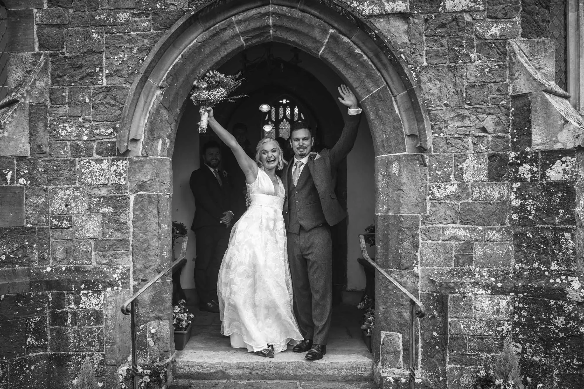 Bride-groom-arms-in-the-air-exiting-church-Whimple-Devon.jpg