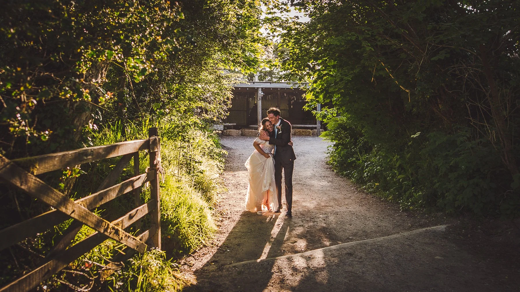 Bride and Groom share a loving embrace backlit by a golden hour sun at Nancarrow Farm wedding