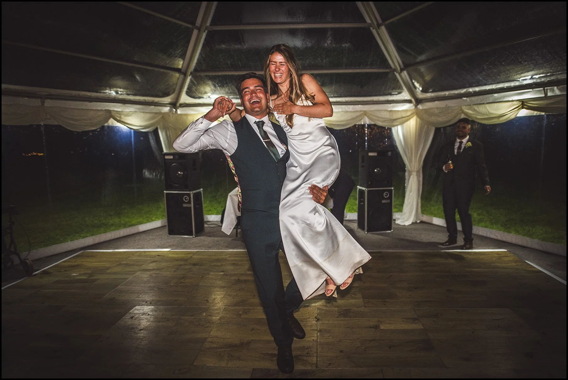 groom lifts bride in the air at first dance, in a marquee wedding, Devon