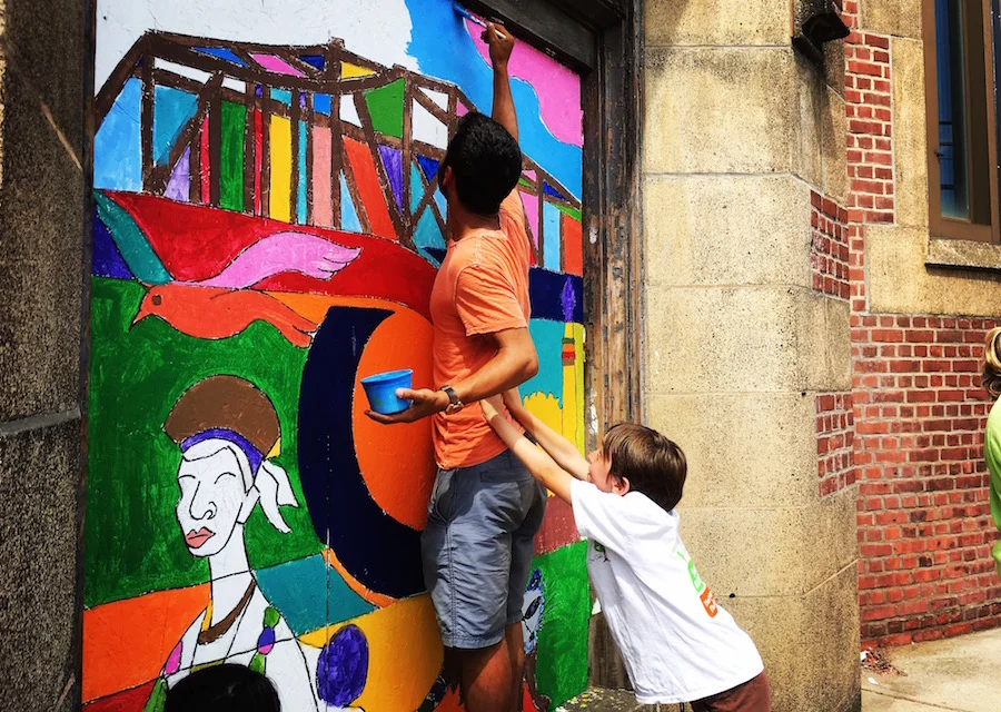 Lior Trestman and Sawyer Christmann help each other get the hard-to-reach spots earlier this year, as they paint a community mural at the vacant Strong School. For me, this image has always reflected what The Arts Paper stands for: Supporting community members to civically-oriented work—and doing that work ourselves—with small but steady hands. Lucy Gellman Photo. 