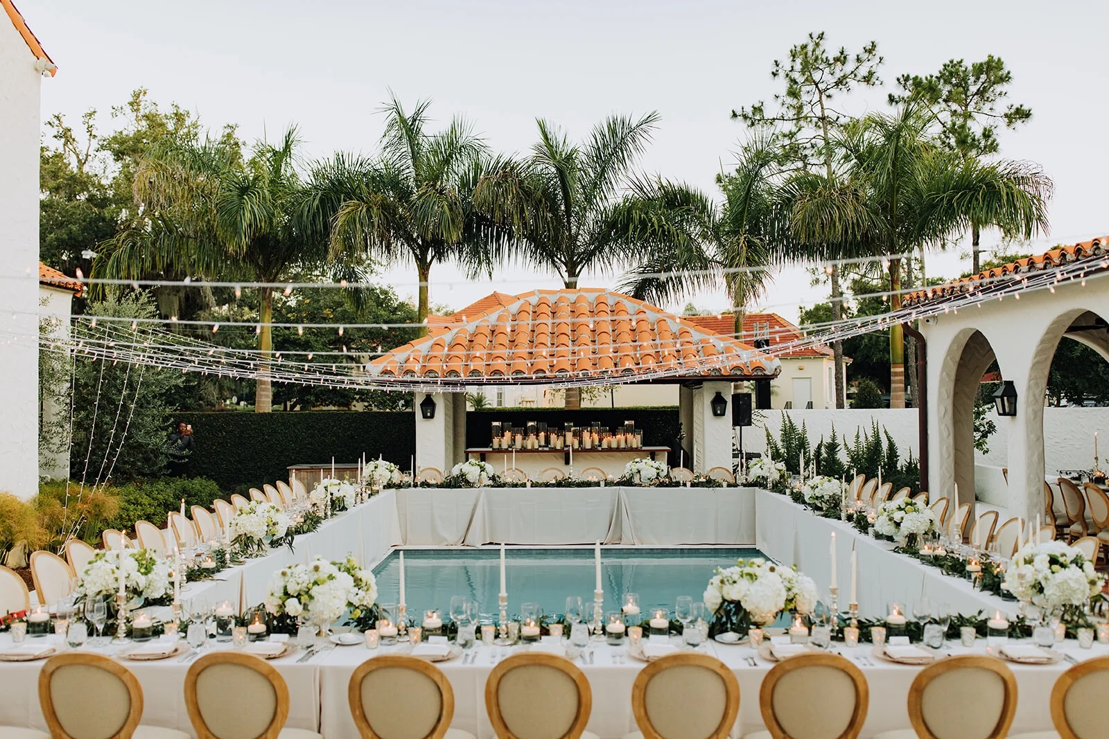 Pool side wedding reception in Winter Park with white flowers and market lights