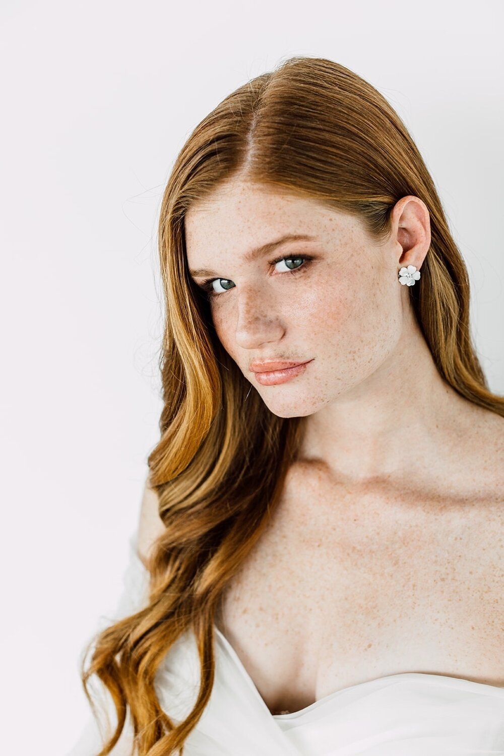 Model wearing pearl bridal earrings from Maria Elena Headpieces. They are a stud with a floral shape