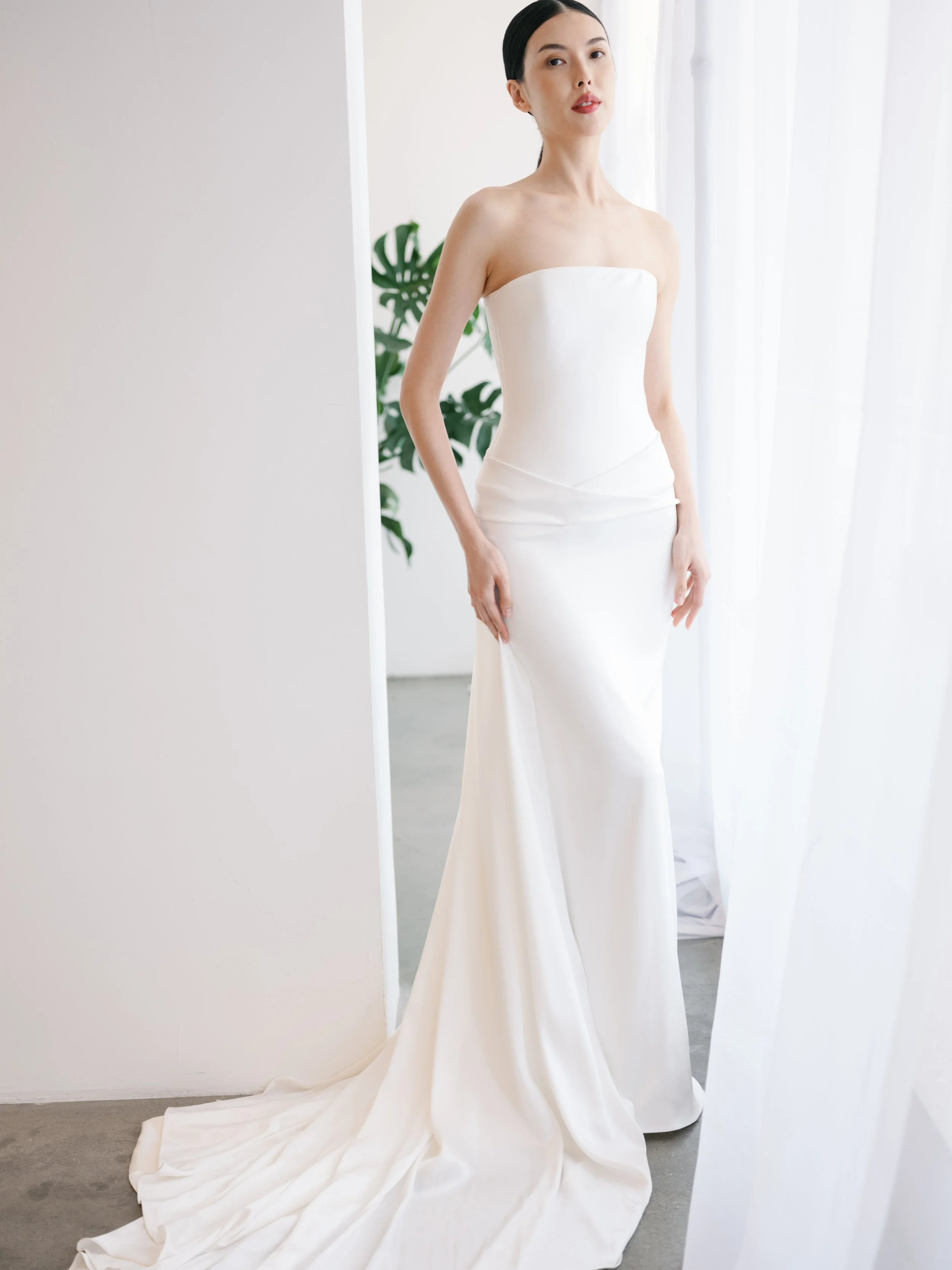 Chic classic simple satin wedding dress. Sheath wedding dress with structured bodice. Corset top with waist draping wedding dress. New KYHA gowns in orlando florida