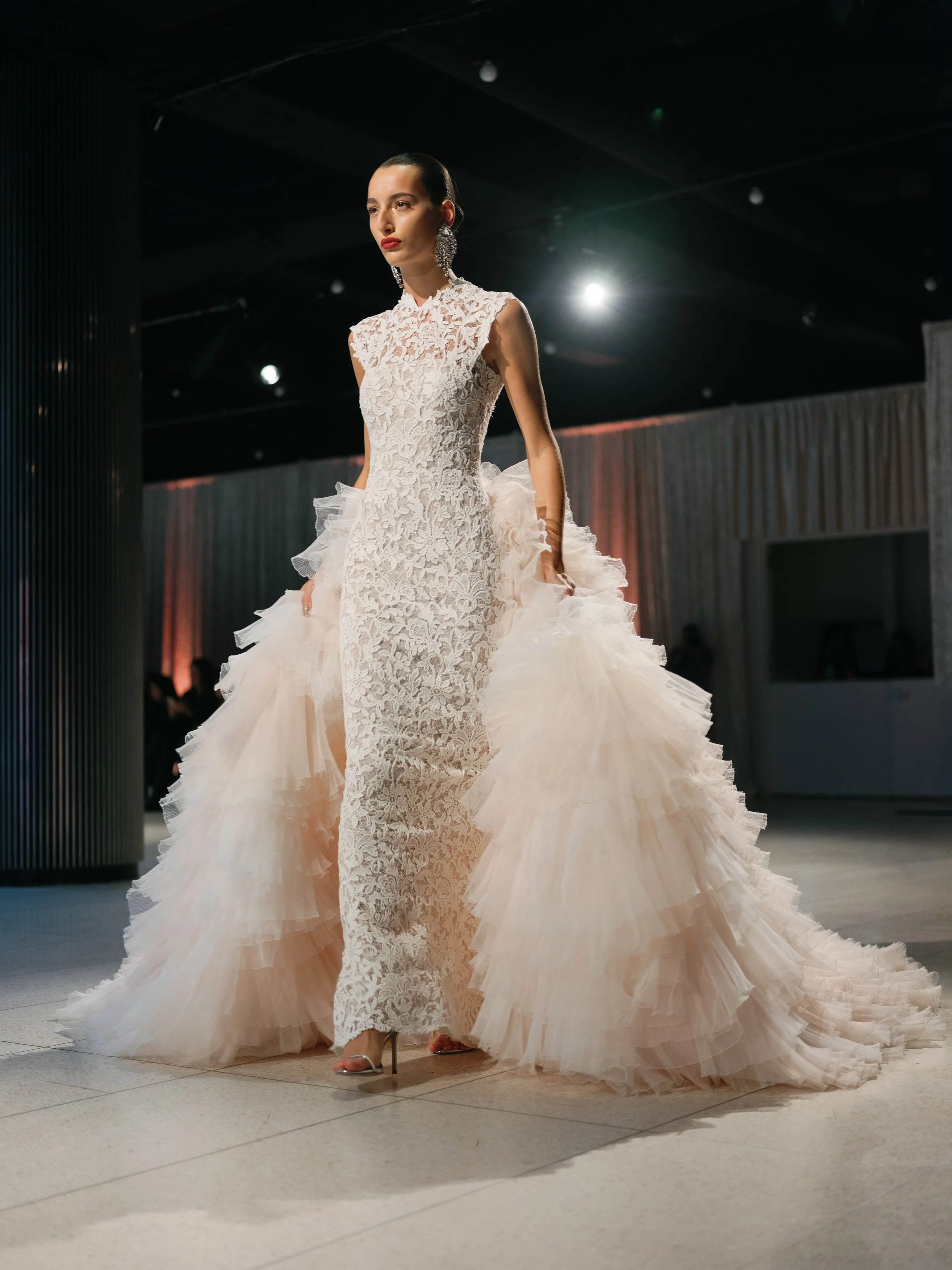 Autumn wedding dress with tulle overskirt . Textured overskirt over full lace wedding dress walking the new york fashion week. High neck lace wedding dress . Fun textured overskirt wedding dress. Pink toned wedding dress with lace halter neck