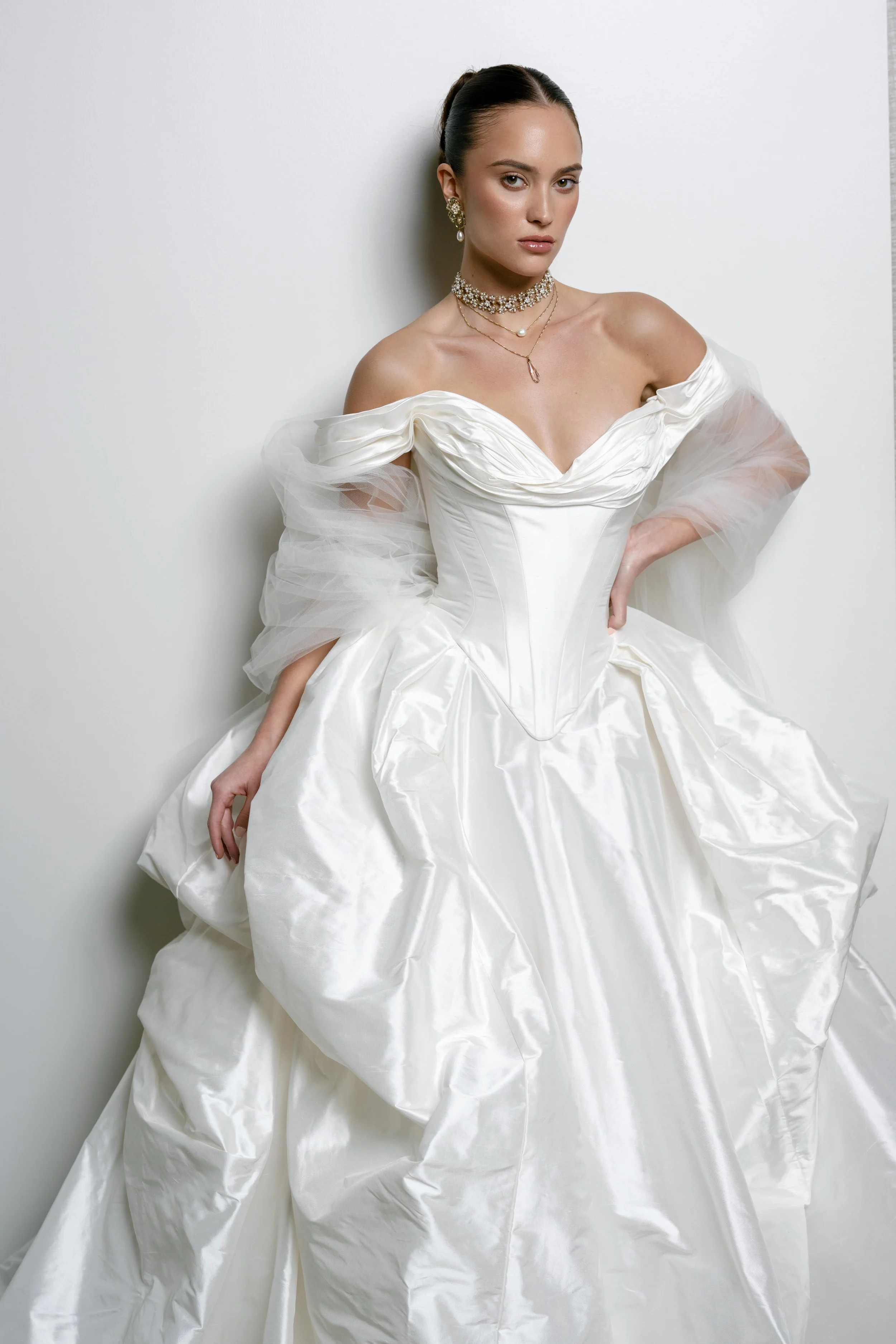 Off the shoulder ball gown with dramatic basque waist wedding dress. Rouched neck line wedding gown with skirt pick ups. Unique wedding dress with corset top. Taffeta material wedding gown by Ines Di Santo