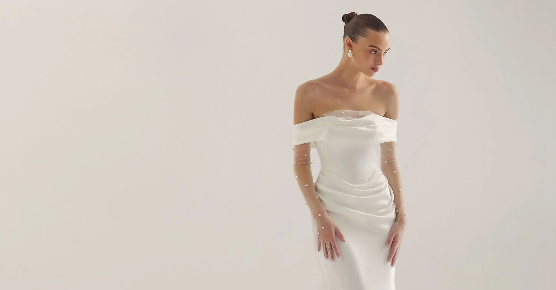lihi hod off the shoulder wedding dress. off the shoulder satin wedding dress with draping at the waist and a basque waist line. strapless satin wedding dress with pearl tulle sleeve detail.