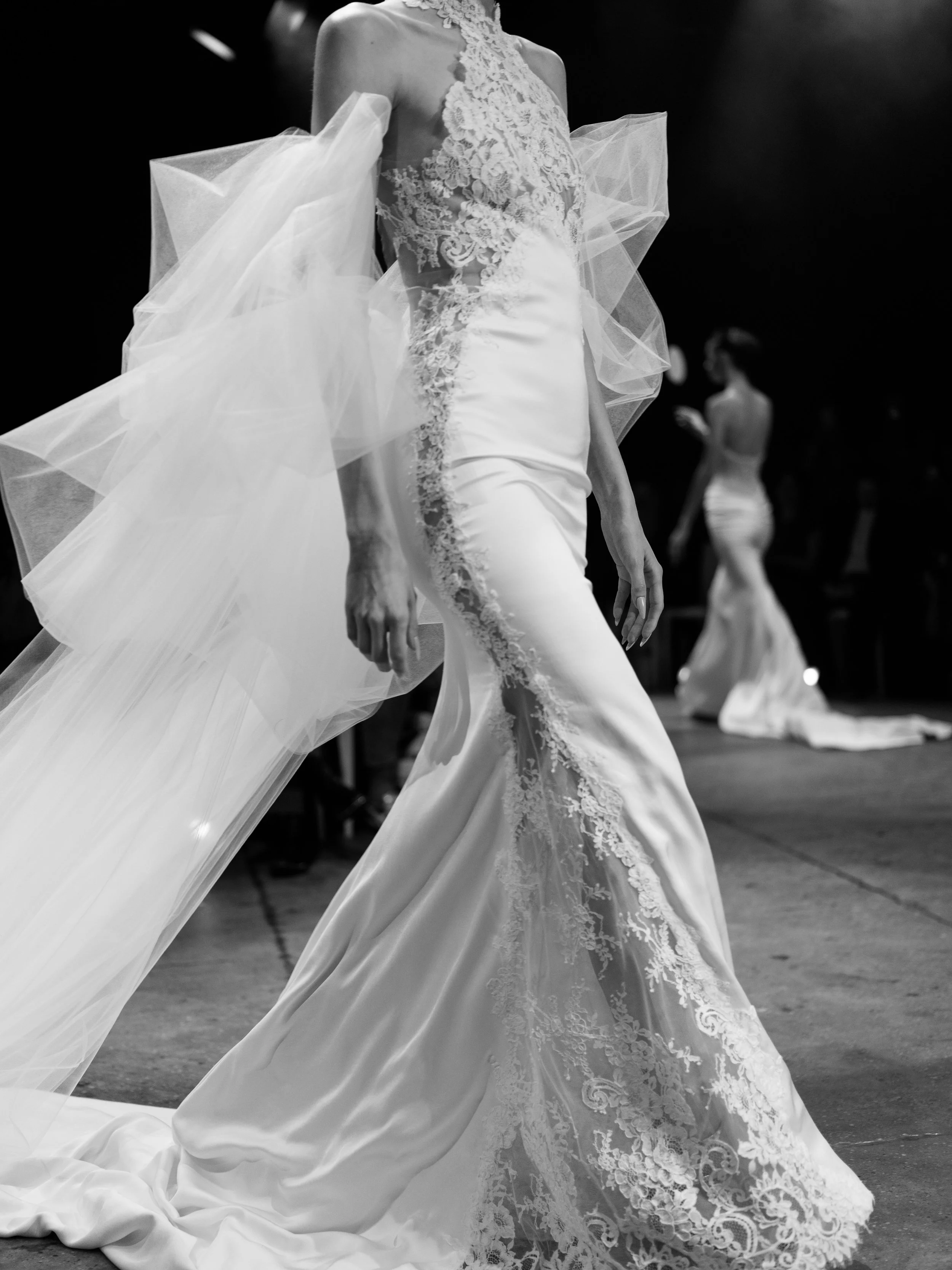 lace and satin halter neck wedding dress walking the 2027 bridal fashion week runway. ines di santo 2027 spring collection lace high neck wedding gown. sheath lace wedding gown with tulle cape.