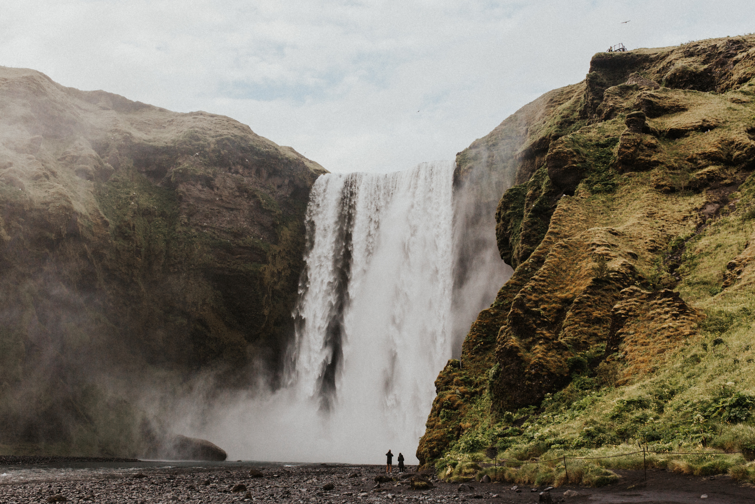 Distance shot of couple looking at Skógafoss waterfall in Iceland.jpg