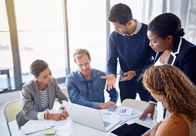 Leaders gathered around a laptop for a leadership moment