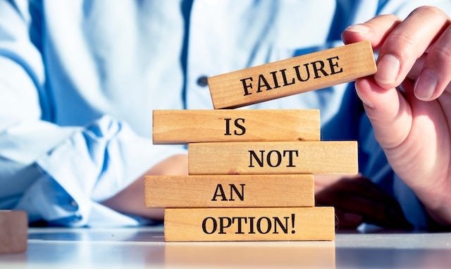 person holding wooden blocks that read failure is not an option!