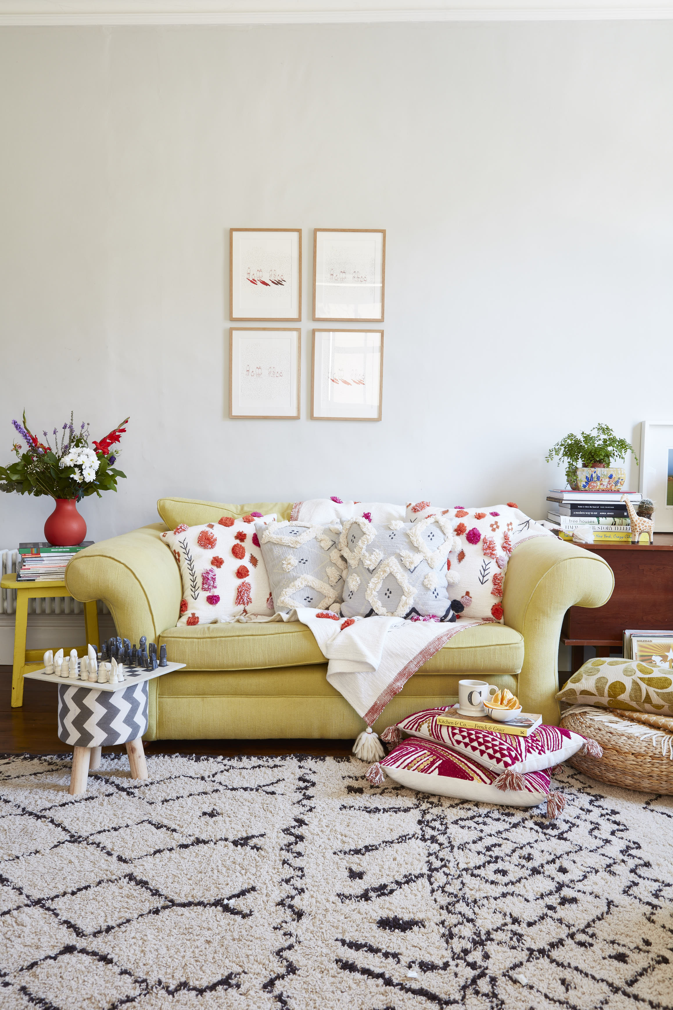 Cushions and throw , Anthropologie . Wicker pouffe. Ikea. Sofa and sideboard, both Heals (Sofa was recovered in yellow linen by local upholsterer). Artwork by graphic designer Darren Howat. Rug, La Redoute. Three-legged stool, Wilko.com and yellow stool, bought secondhand and repainted. Neo-orange rubber vase, Polyvore.com